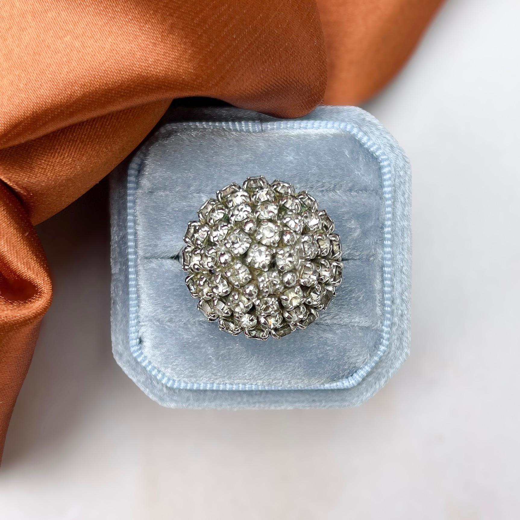 This dramatic and shimmering cocktail ring was made in the 1970s by Christian Dior. 

Condition Report:
Excellent

The Details...
This rhodium plated ring features a dome design and is detailed with round, colourless rhinestones. All of the stones