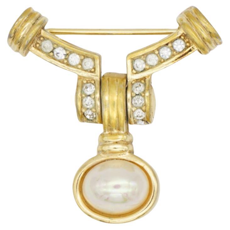 Christian Dior 1970s Vintage Unisex Movable Dangle White Pearl Curved Crystals Badge Modernist Brooch, Gold Tone

Very good condition. Light scratches or colour loss, barely noticeable. 100% genuine.

A unique piece. This is gold plated stylised