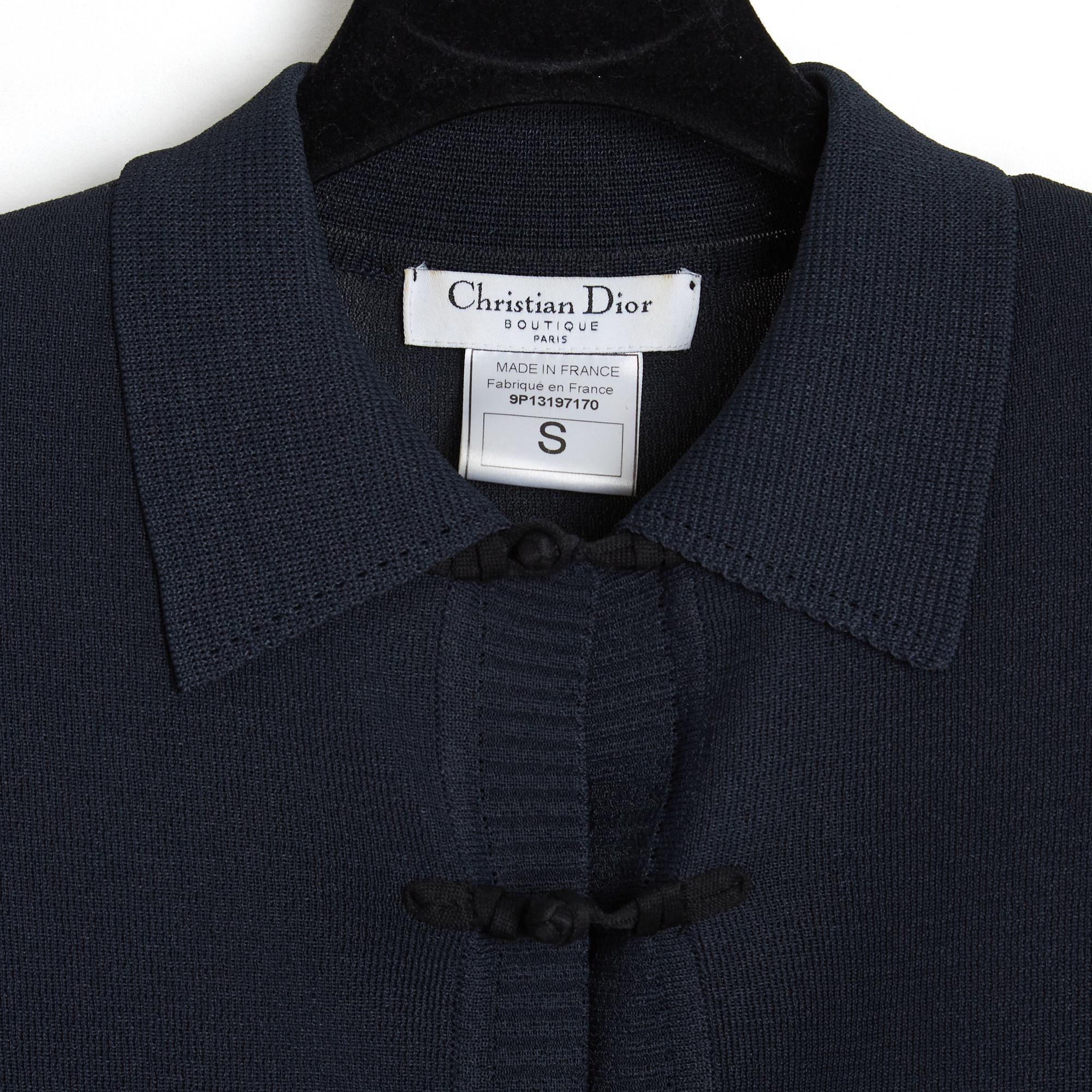 Top ou veste Christian Dior de la collection SS1999 de John Galliano en maille viscose mélangée bleu marine (presque noire), col polo fermé sur toute la hauteur par une série de boutons en galon d'inspiration asiatique, manches longues en dentelle