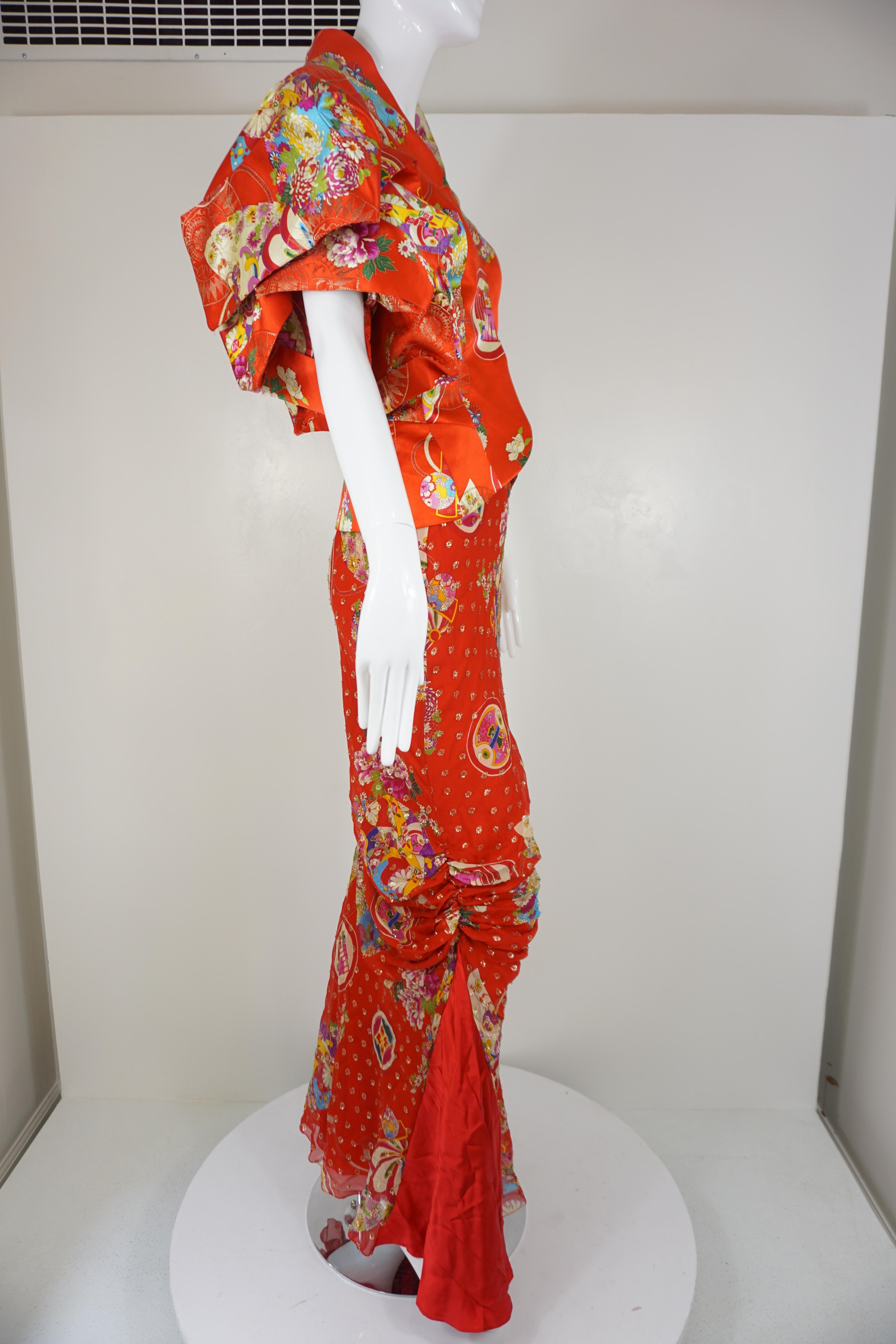 John Galliano designed Christian Dior jacket and skirt, from the 2003 runway collection, is featured in a red silk blend, with a colorful Chinese pattern and metallic jacquard stitching. The fully lined skirt has an exterior that is ruched on both
