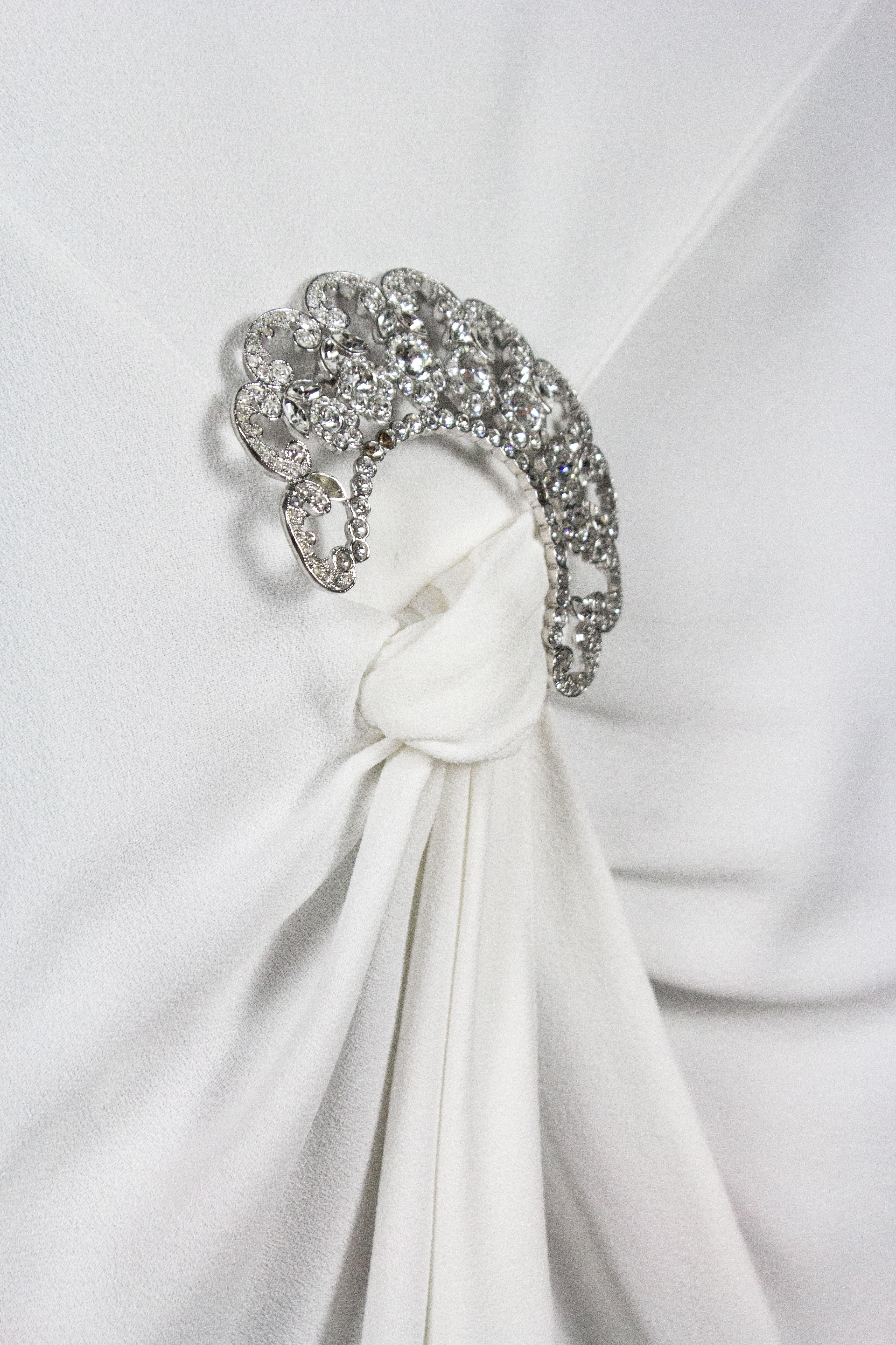 Christian Dior by John Galliano dress, from the Spring/Summer 2004 collection. White with satin interior, detachable diamante brooch set on the draped skirt, and front slit. Open style cowled back detail. Fabric covered buttons on the side with a