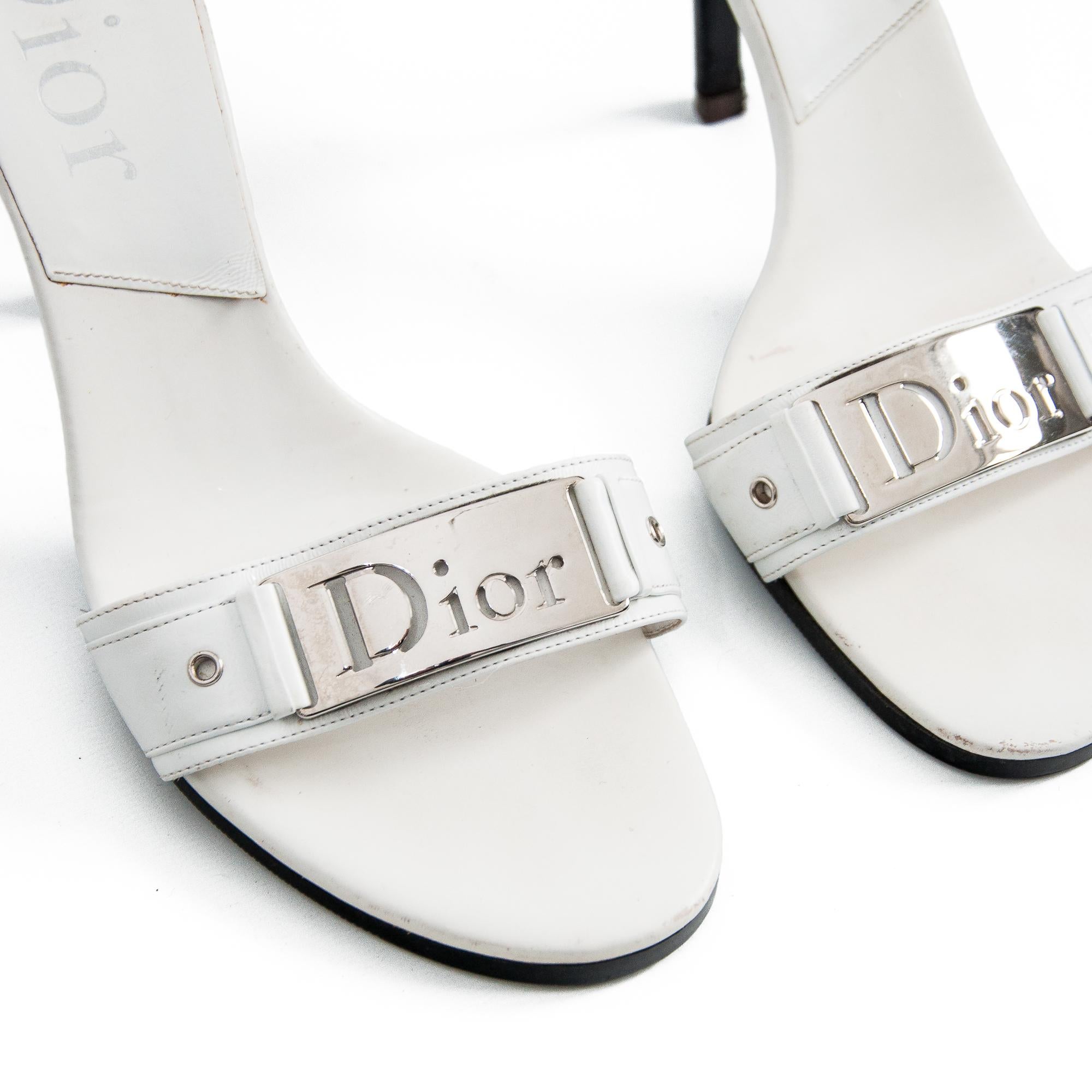 Mules à talons hauts vintage Christian Dior par John Galliano pour la collection printemps-été 2006. 

Construction en cuir blanc.

Plaque Dior chromée sur le bracelet.

Semelle et talon noirs contrastés.

Vintage By, 2006.

Fabriquées en