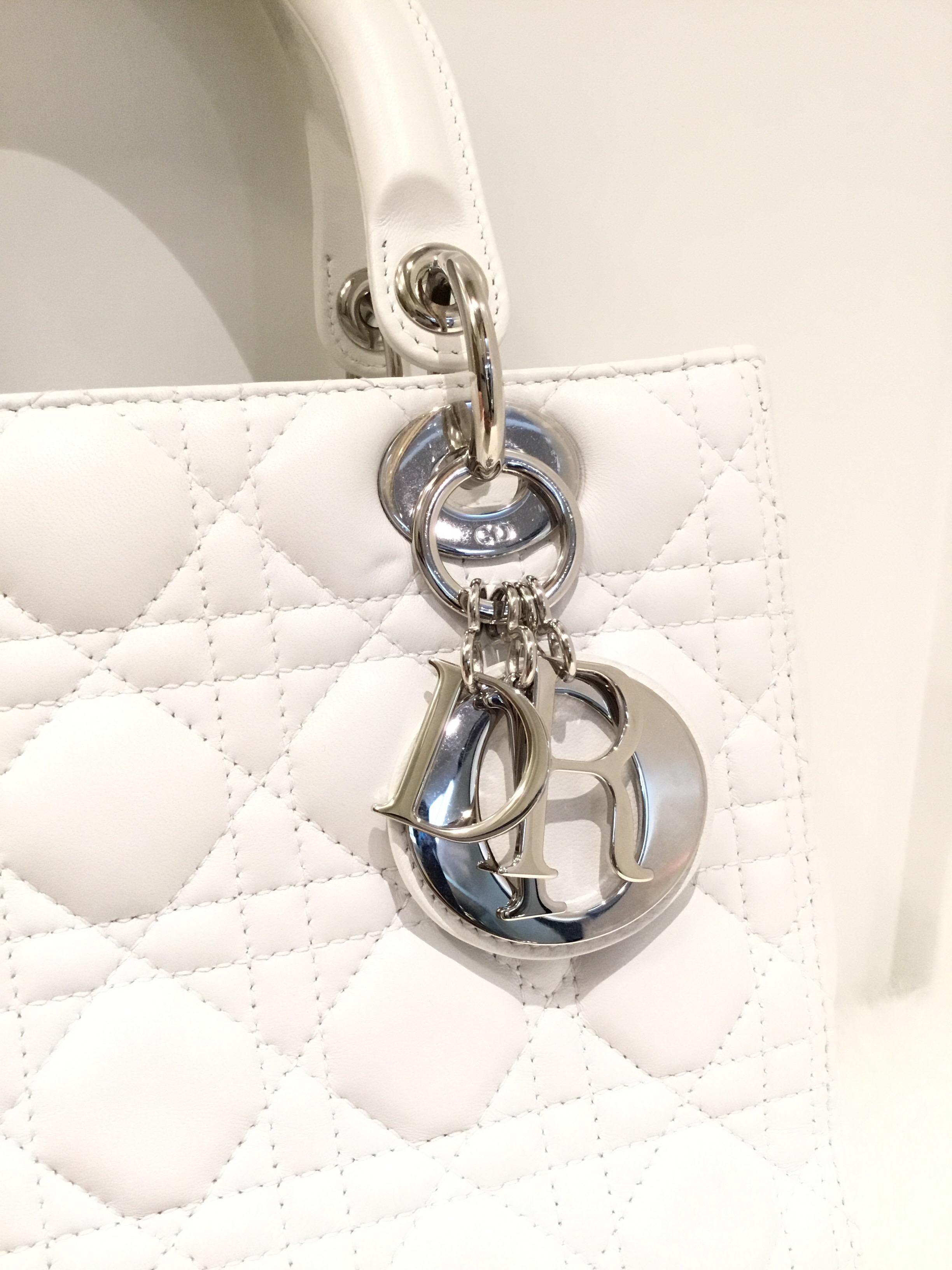 Pristine white Christian Dior “Lady Dior” bag has a top handle or a removable crossbody strap, silver-tone hardware throughout, and a top zipper closure. Bag is fully lined and has one zipper pocket. Minimal wears throughout (see photos).

