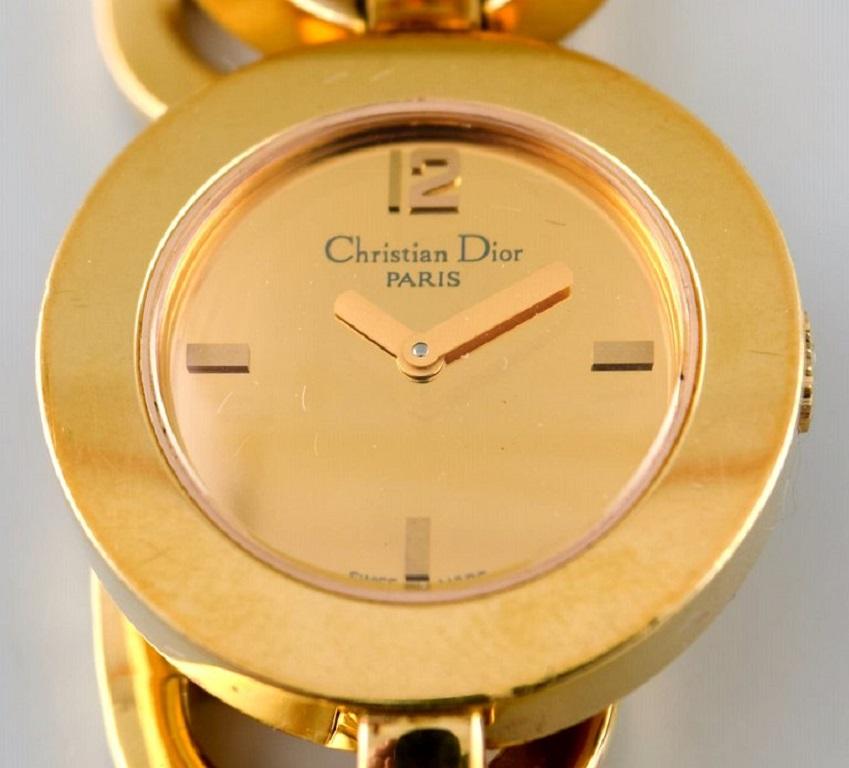 Christian Dior: A lady's wristwatch of gold-plated steel. Quartz. 
Gold-coloured mirror dial with gold-coloured hands. 
Integrated bracelet of gold-plated steel.
Circumference app. 17 cm.
One extra link included.
Watch diameter 25