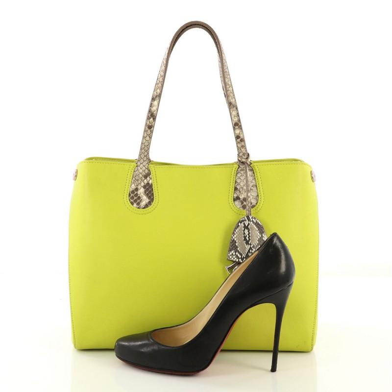 This Christian Dior Addict Shopping Tote Leather and Python Small, crafted in neon green leather with genuine brown python, features genuine python skin handles, side snap buttons, Dior charm accents and silver-tone hardware. Its magnetic snap