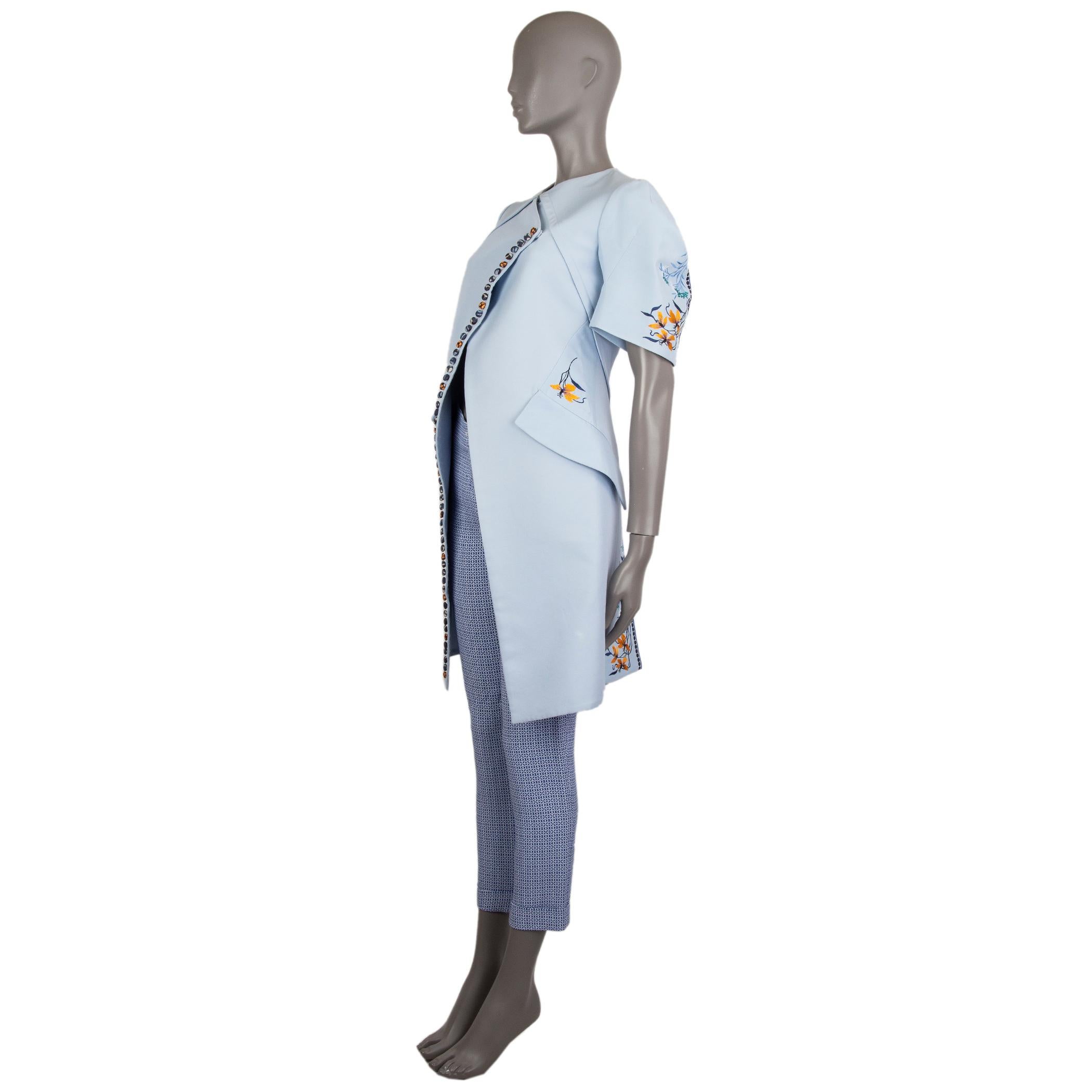 Christian Dior short-sleeve coat in pale blue cotton (62%) and silk (38%). With flower embroideries, diagonal double-breasted front, v neck, decorative fabric buttons down the front seam, pouf sleeves, two flap pockets on the sides, and box pleating