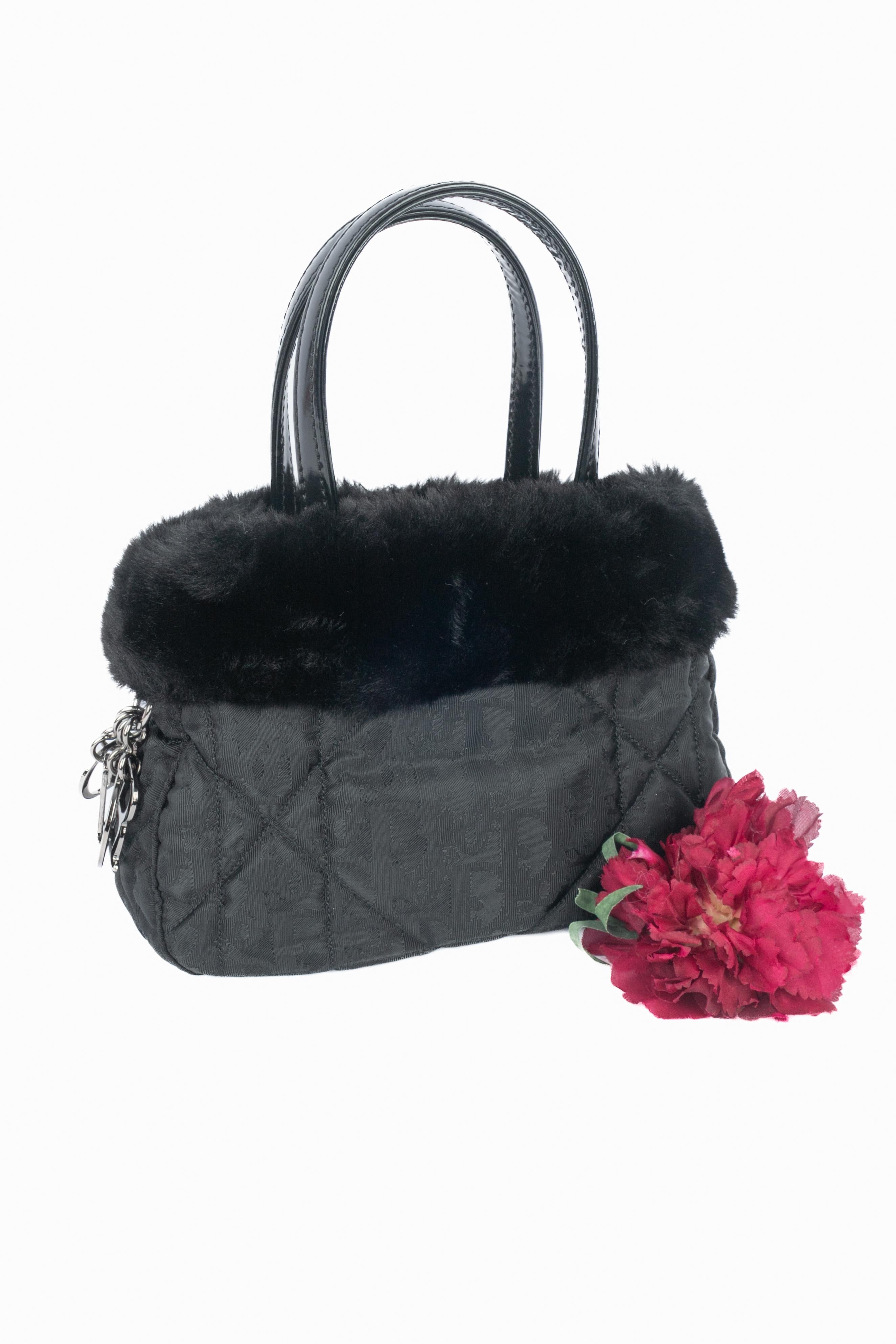 DIOR - (Made in Italy) Black monogram canvas bag topped with faux fur, and ornamented with silvery metal charms with the house name, and with black patent leather handles. Piece with a serial number. 1998 Spring-Summer Collection under the artistic