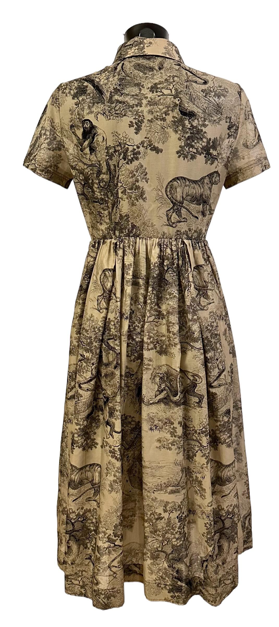 This pre-owned shirt dress showcases the House's hallmark Toile de Jouy motif in black and beige. 
Craftted in cotton voile, it boasts a long and fluid silhouette enhanced by a spread collar, pleated details at the waist and short