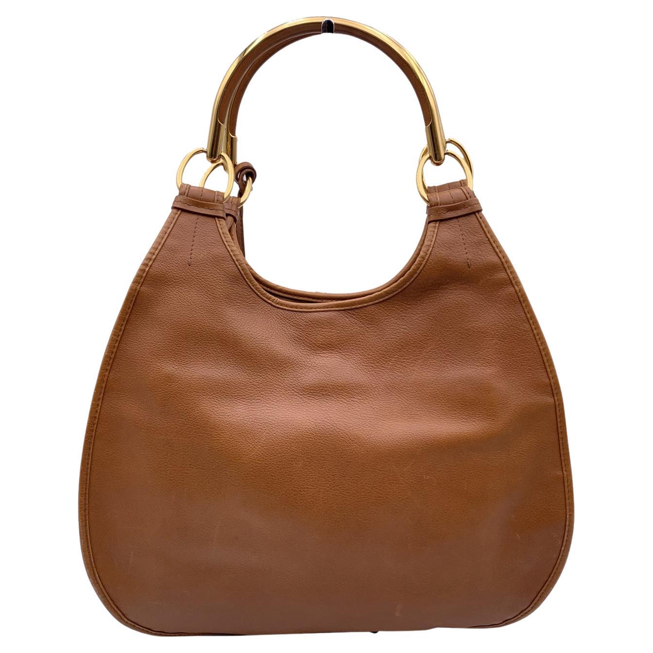 CHRISTIAN DIOR 'Dior 61' hobo bag in leather, designed by John Galliano, from the 2008/2009 collection. The bag is inspired by the design of the 60s. 2 gold metal handles. Gold metal D-shaped letter charm attached on the handle. Tan leather. 2 front