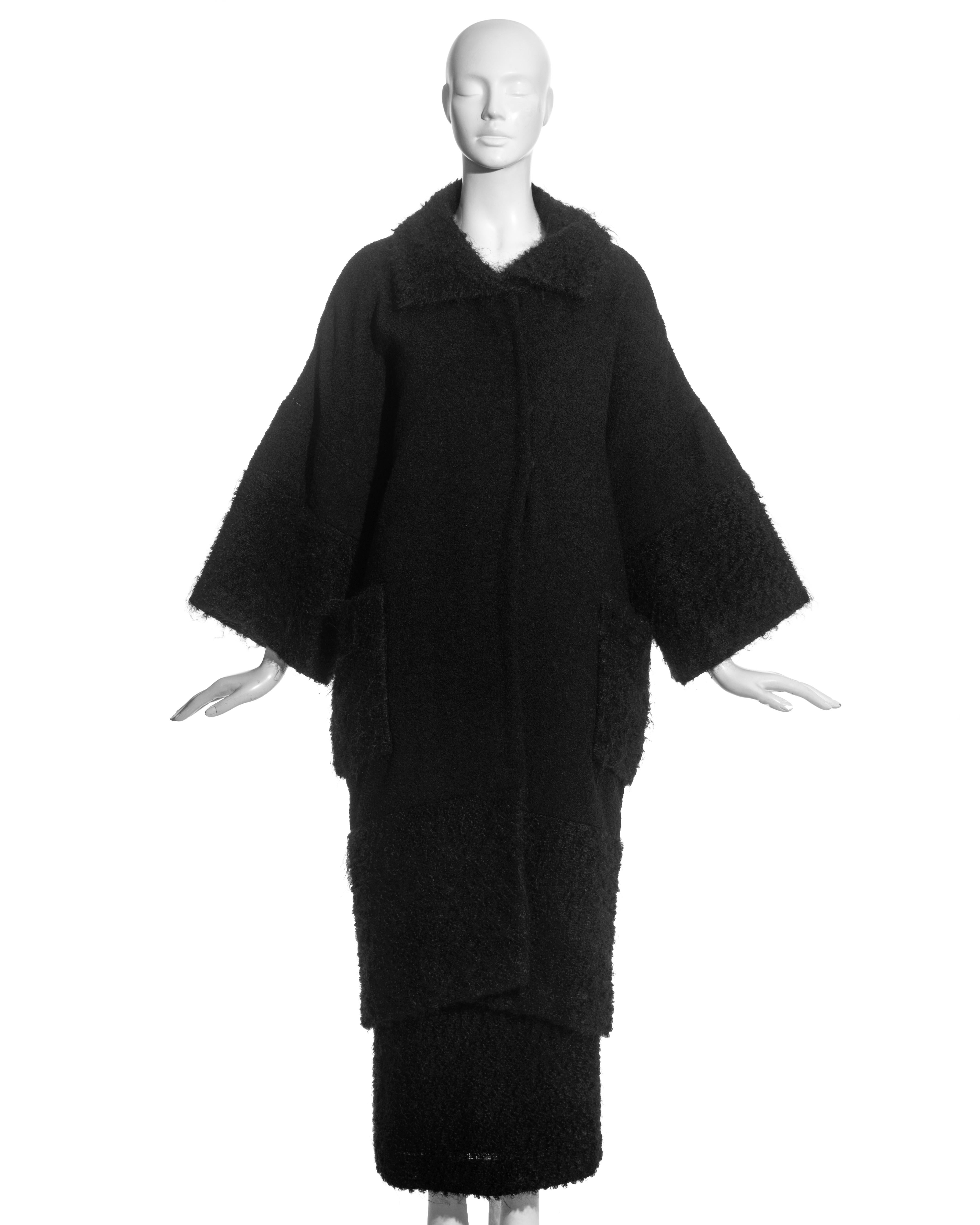 Costume jupe en laine bouclée et mohair noir Christian Dior by John Galliano comprenant : manteau ample à manches larges, deux poches plaquées sur le devant et doublure en soie. Jupe longueur cheville avec grande ouverture boutonnée au dos.