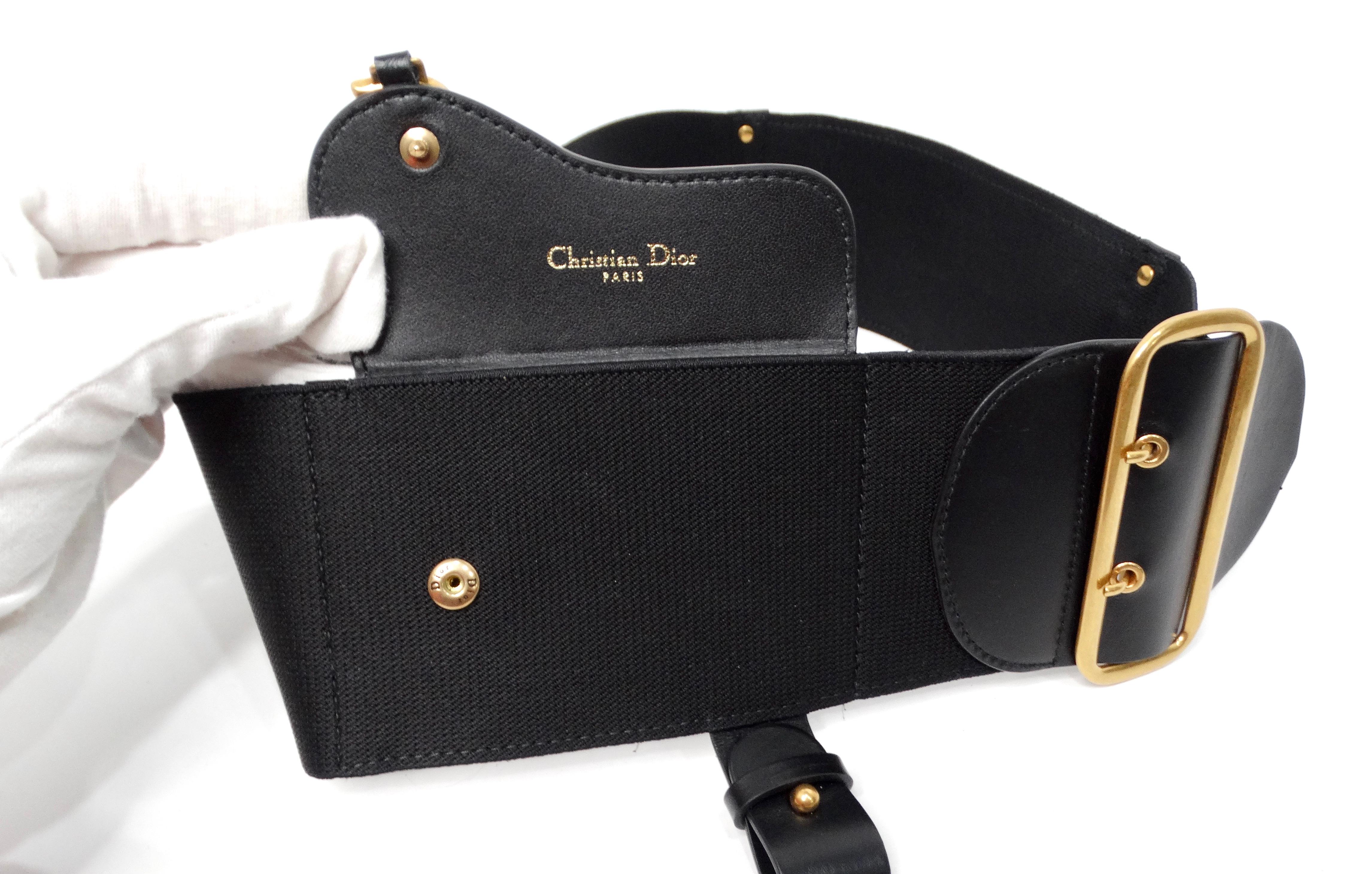 The Christian Dior Black Calfskin & Elastic Saddle Belt is the epitome of modern luxury, seamlessly blending functionality with high fashion. This wide belt features a striking combination of black elastic and sleek black calfskin leather detailing,
