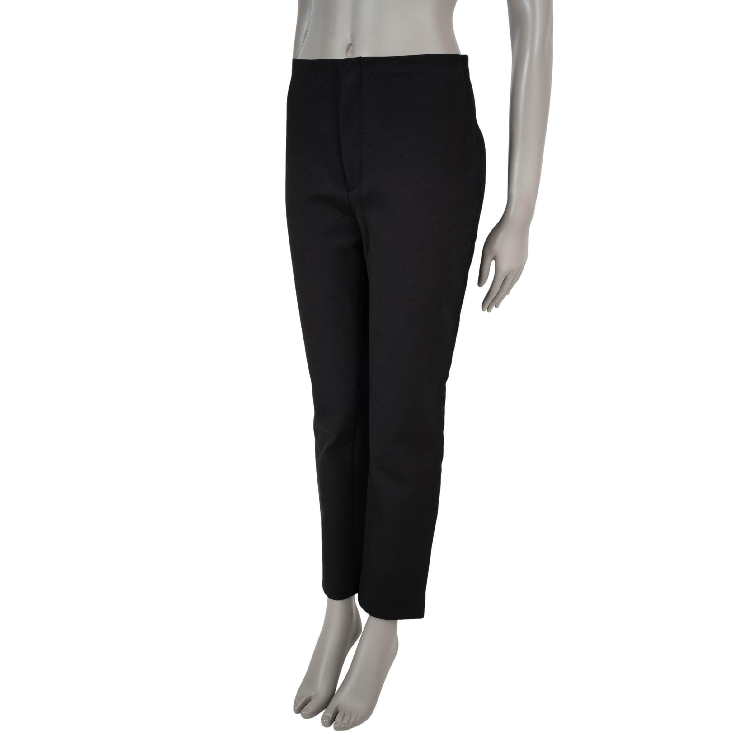 Questi pantaloni 100% autentici di Christian Dior in gabardine nera elasticizzata di cotone (54%) e poliammide (42%) offrono una silhouette raffinata e strutturata. Progettati a vita alta e con gamba aderente, sono caratterizzati da strisce laterali
