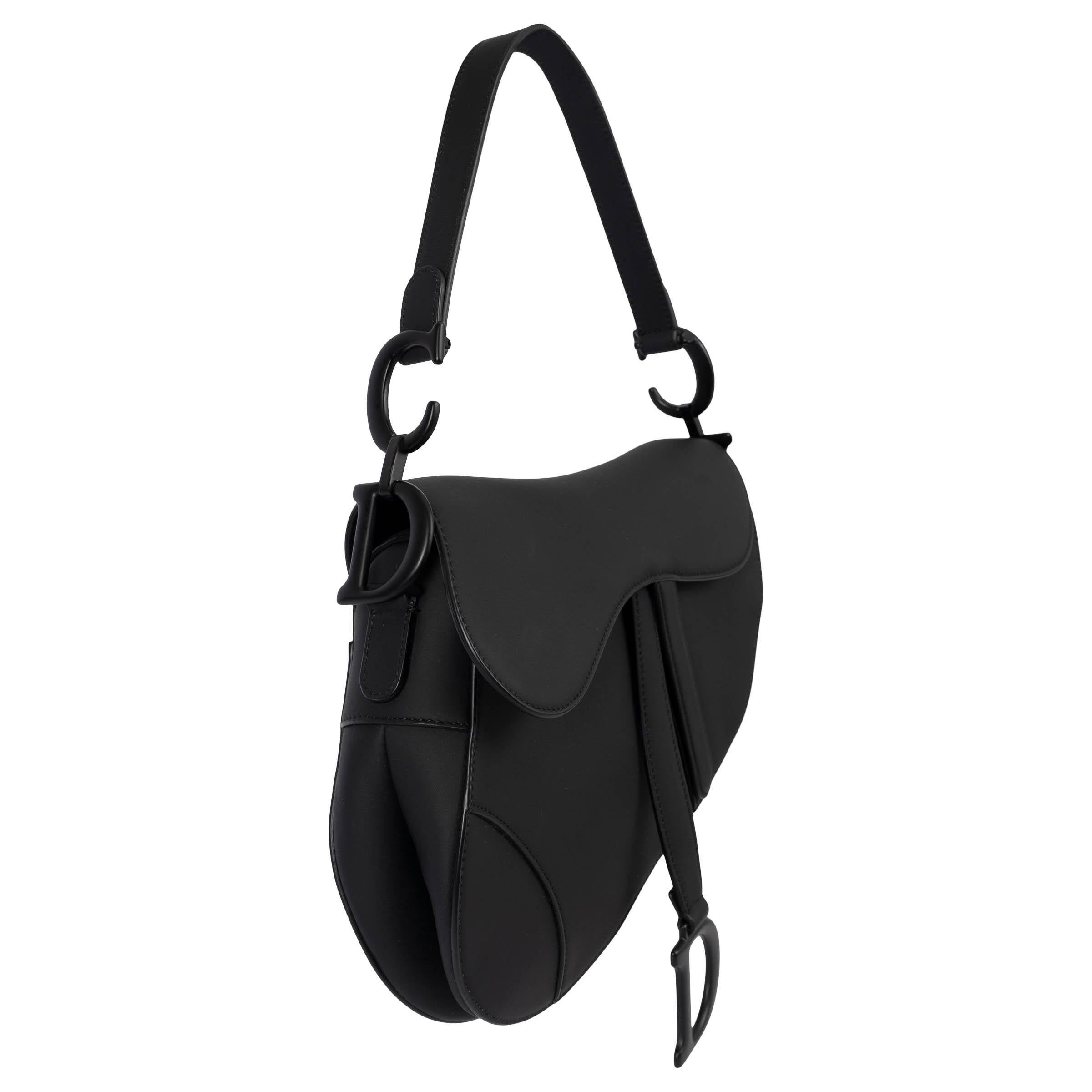 100% authentic Christian Dior Saddle bag in black smooth ultramatte calfskin. The legendary design features a Saddle flap with a D stirrup strap and magnetic pull, as well as a black matte metal CD signature on either side of the handle. The design