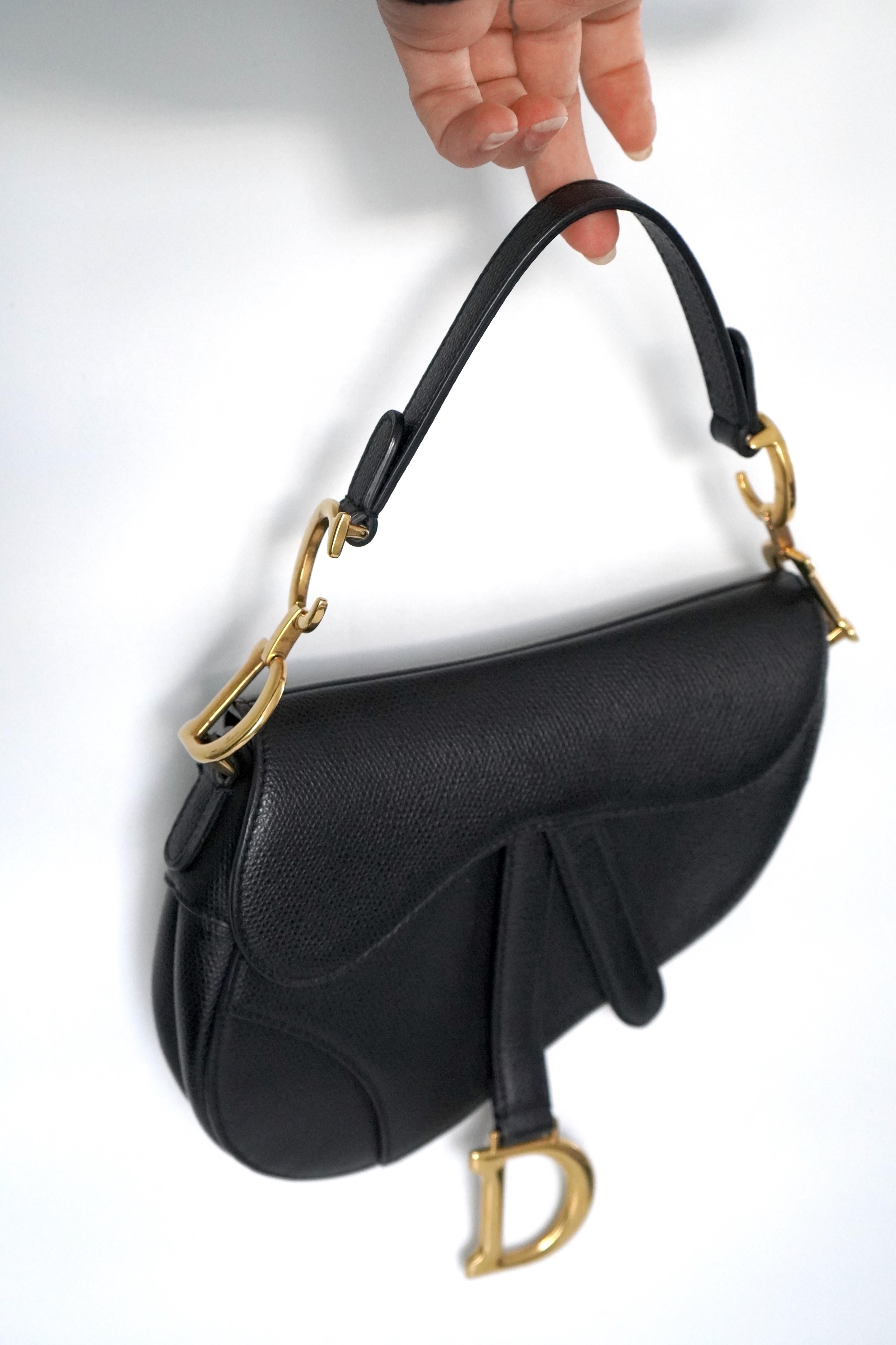 Christian Dior Black Leather Mini Saddle Bag 

• Grained Calfskin
• D stirrup clasp with magnetic strap closure
• CD signature on the strap
• Back pocket
• Made in Italy
• Gold-Tone Hardware
• Flat Handle
• Single Exterior Pocket
• Suede Lining
•