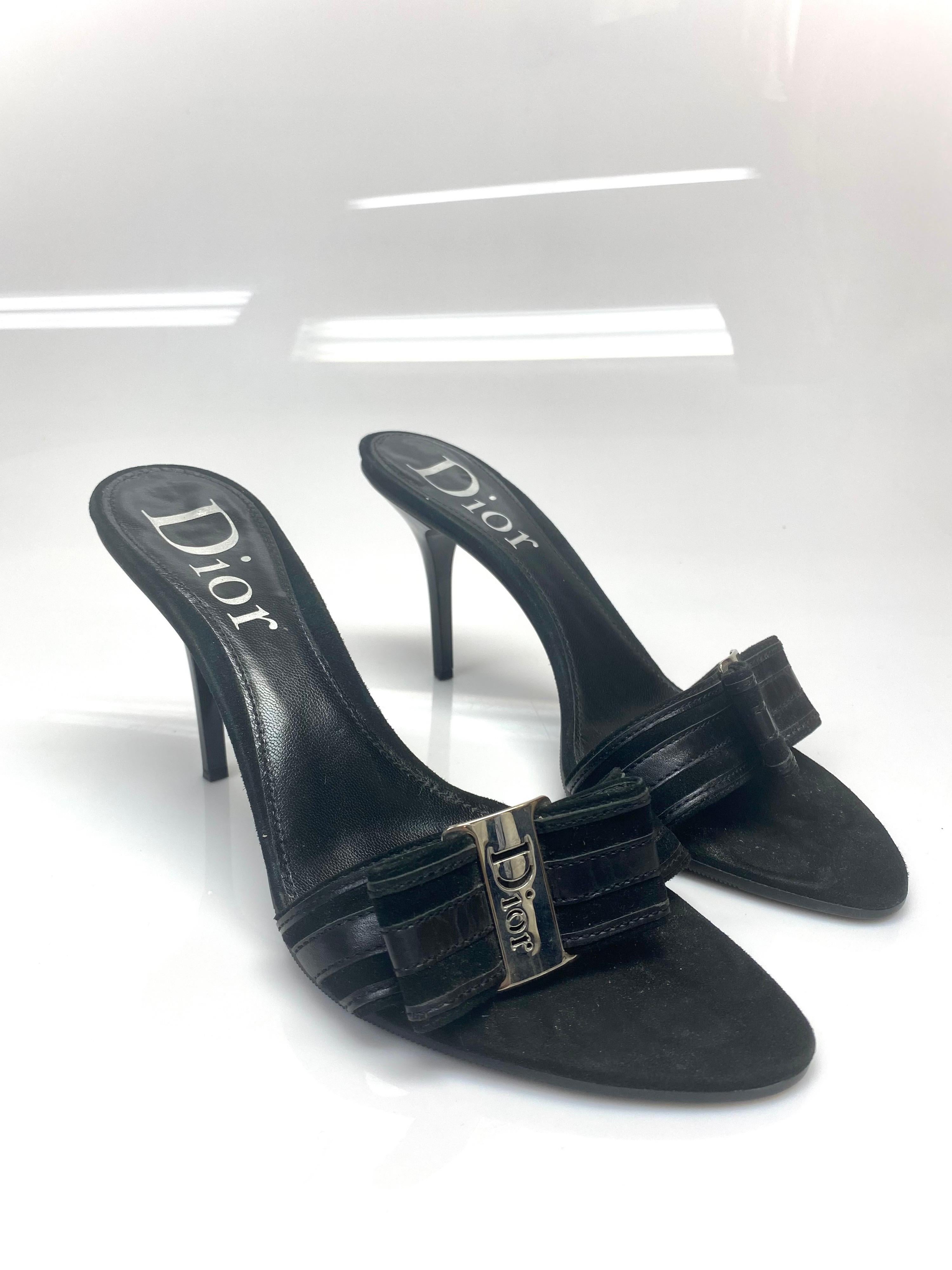 These vintage Dior heeled slides are a truly unique and durable shoe. An engraved Dior silver hardware bow with black striped leather highlights the shoe that gives it an elegant and modern look. The item is in very good condition with some minimal