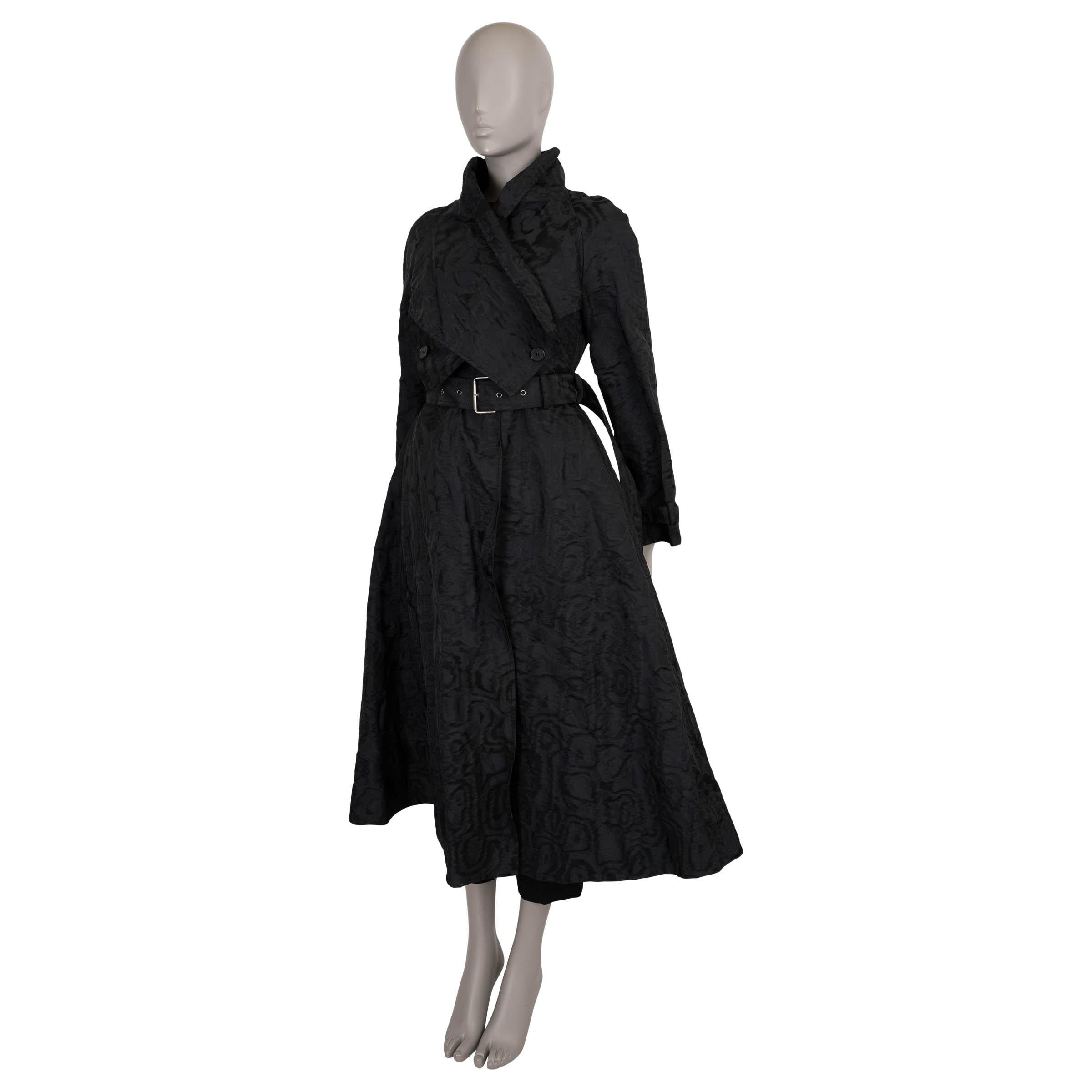 This 100% authentic Christian Dior trench coat is crafted in black technical moiré polyester (89%) with metallic fibers (11%), paired with a removable macrocannage quilted vest in black polyester (100%) with soft polyester padding. The dramatic,