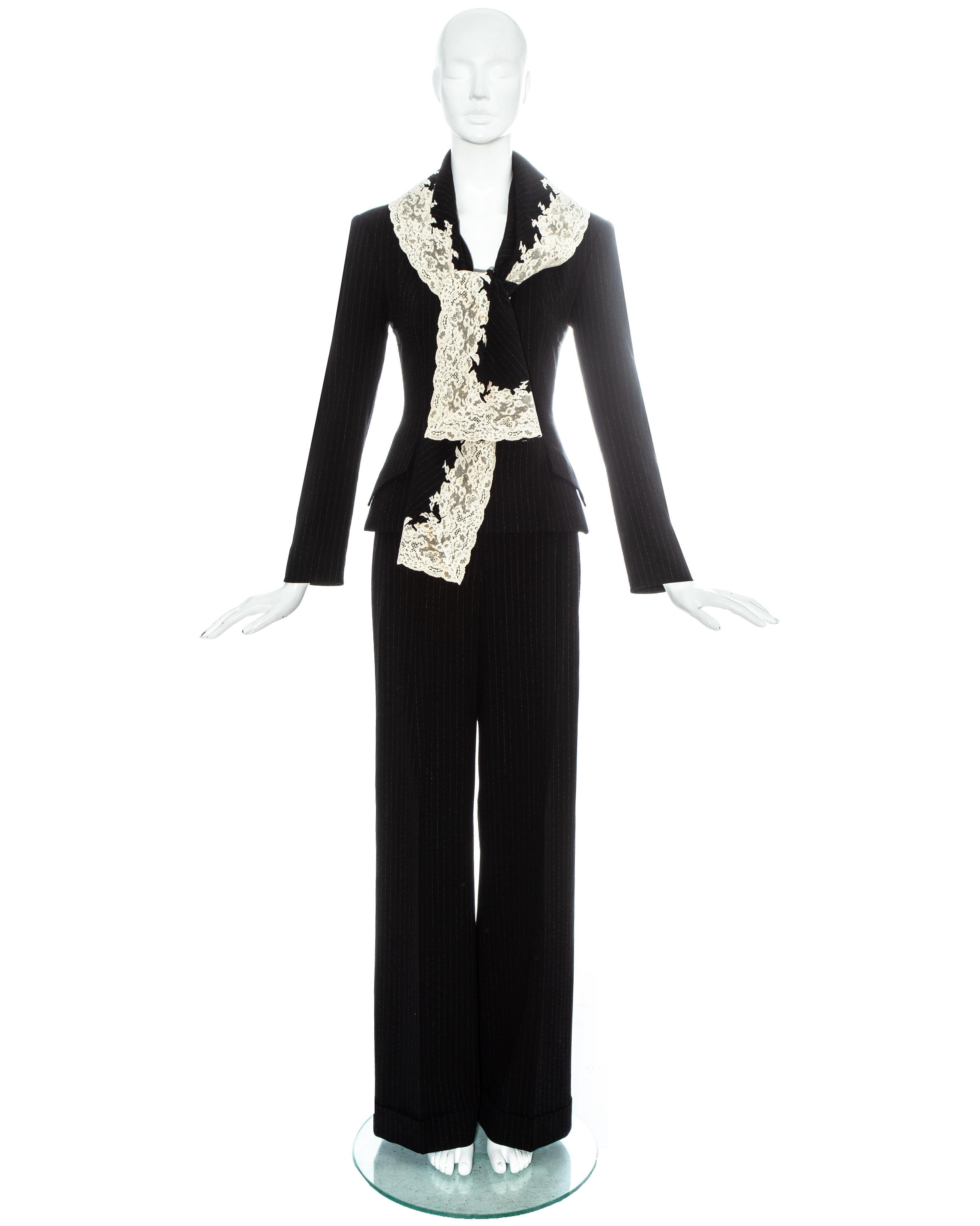 Christian Dior by John Galliano. Black pinstriped wool crepe pant suit edged in white Calais lace. Blazer jacket with shawl attached to the collar, two front flap pockets, fabric button closures and silk lining with embroidered 'CD'. Sold with