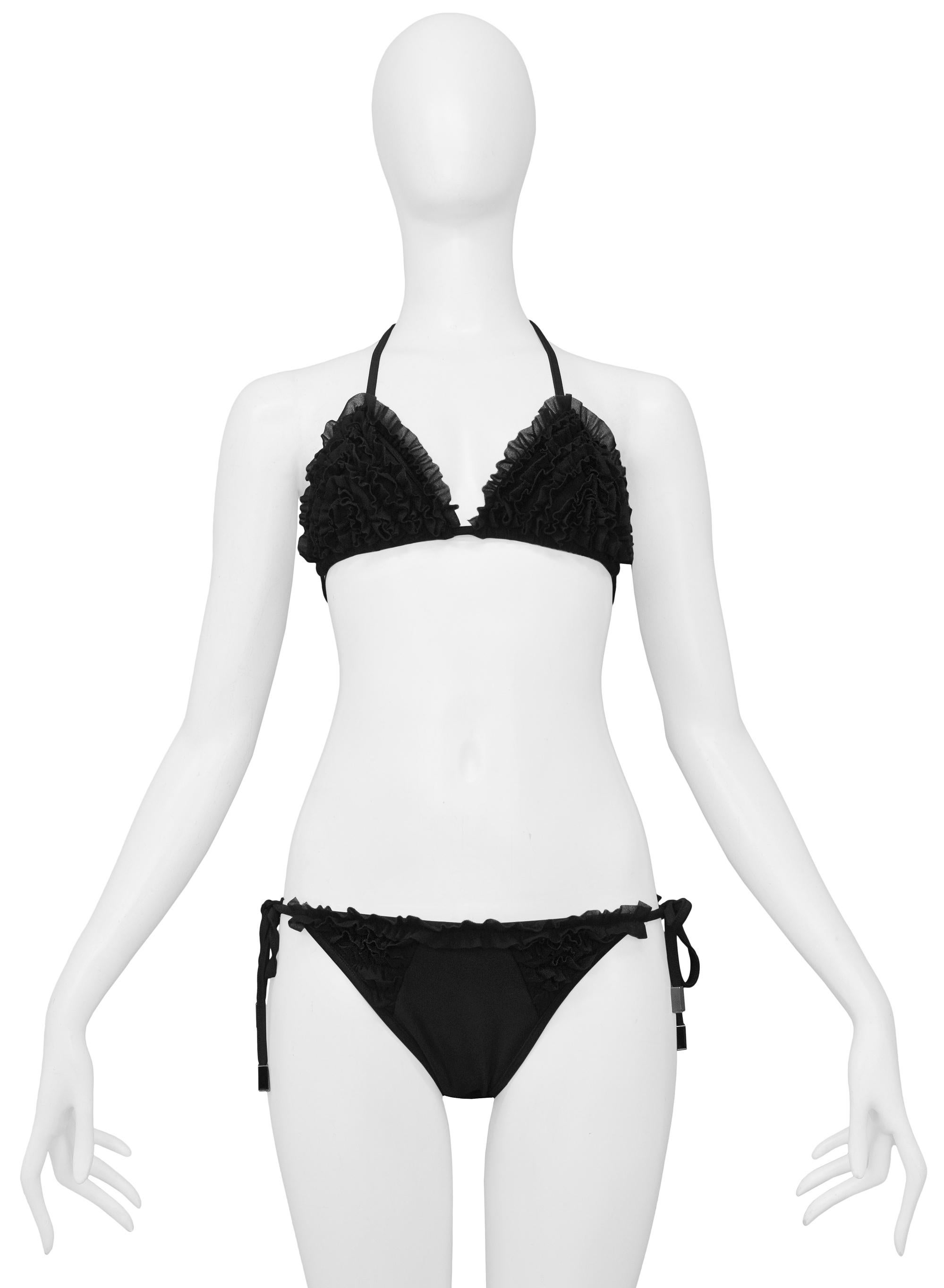 Resurrection is excited to offer a vintage Christian Dior black bikini featuring an adjustable triangle top with ruffles, side tie bottoms with ruffles, and skinny ties with chrome hardware. 

Christian Dior Paris
Designed by John Galliano
Size