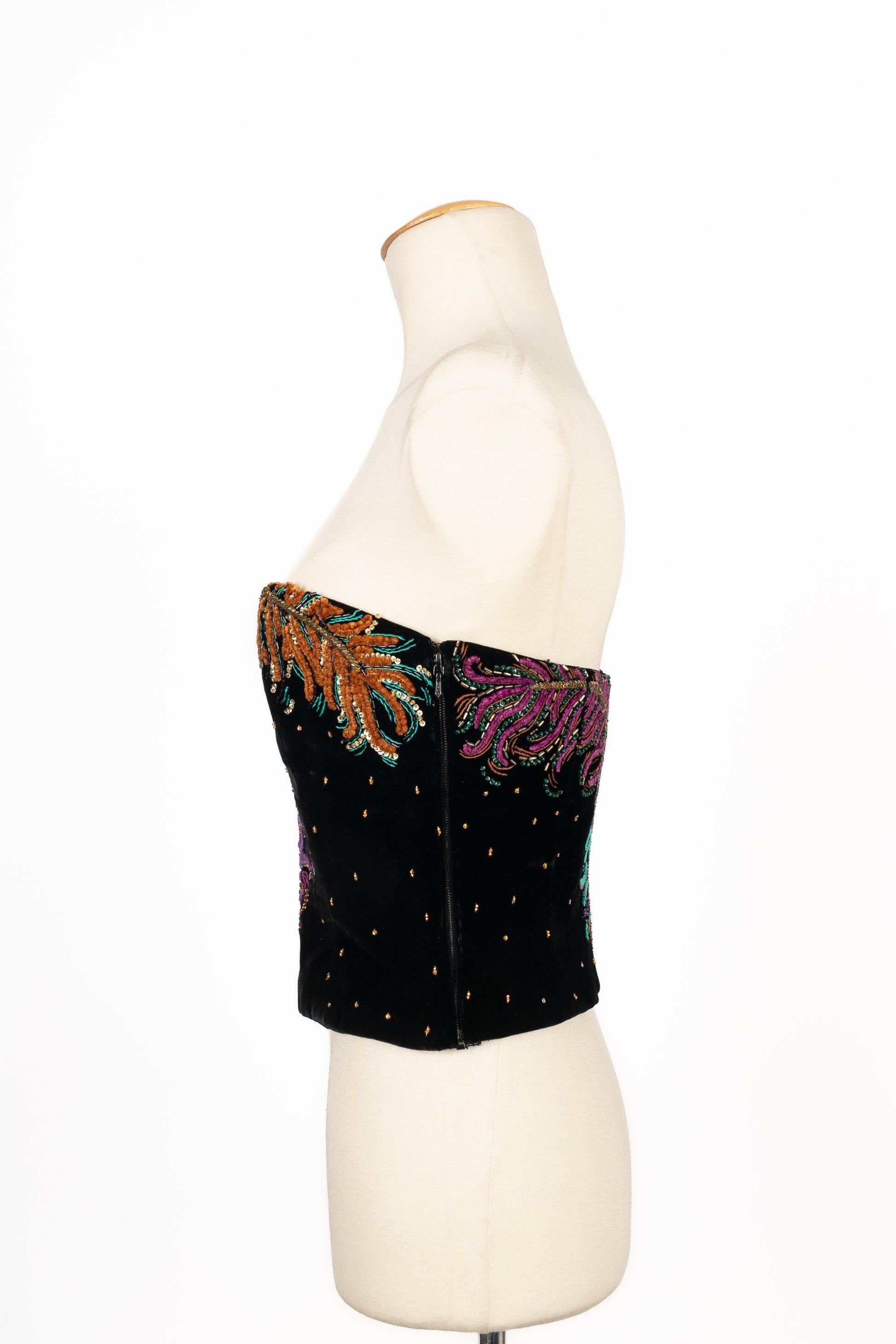 Dior - (Made in France) Black velvet bustier top enhanced with golden sequins and an ostrich feathers pattern in purple, pink, orange, and green tones. No size indicated, it fits a 34FR. A 1989/1990 Collection by GianFranco Ferré.

Additional