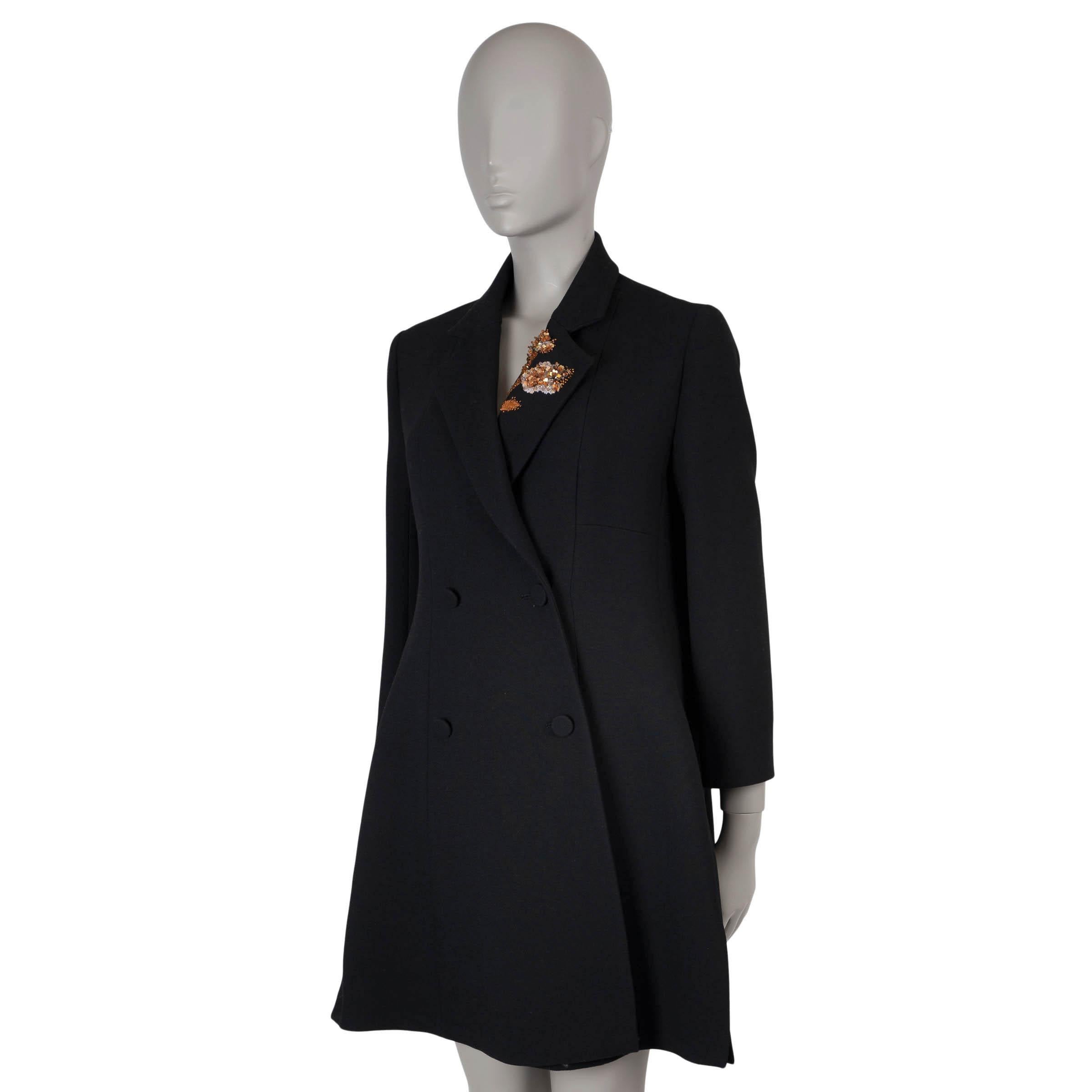 Dieser 100% authentische Christian Dior Zweireiher ist aus schwarzer Serge-Wolle (100%) gefertigt und mit einer auffälligen orangefarbenen, mit Kristallen und Pailletten bestickten Blume auf dem Revers versehen. Dieser elegante Mantel mit