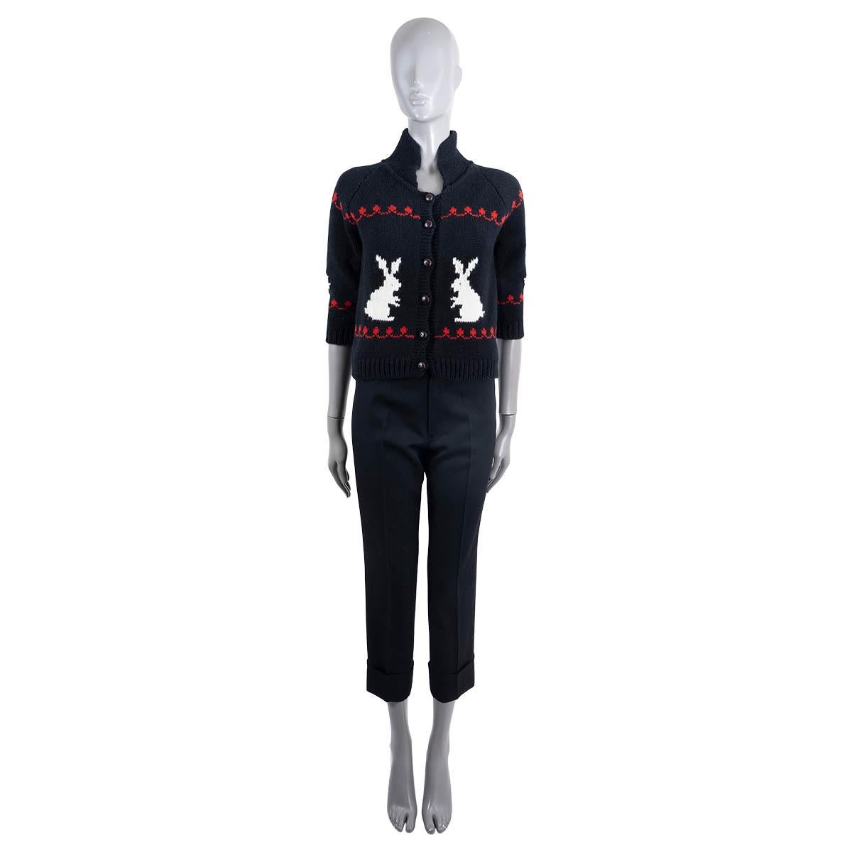 100% authentic Christian Dior cardigan in black wool (70%) and cashmere (30%). With intarsia rabbits in white and details in red, half raglan sleeves (sleeve circumference measured from the neck) and stand-up collar. Closes with brown leather