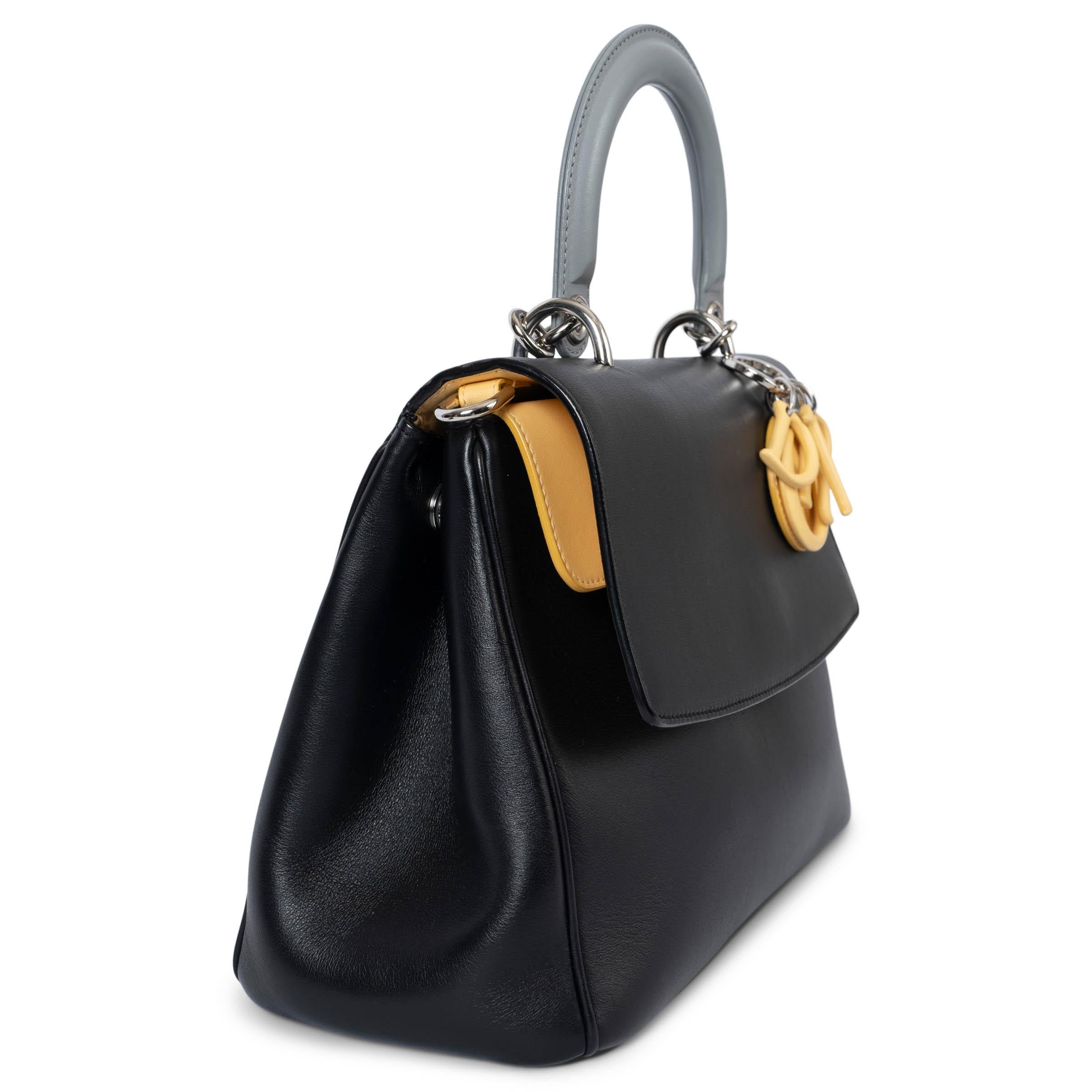 100% authentique Christian Dior Be Dior Petit sac à rabat en cuir de veau lisse noir et jaune avec accessoires argentés, anse grise et breloques DIOR en métal recouvertes. Le sac est muni d'une longue bandoulière amovible, d'un rabat qui s'ouvre