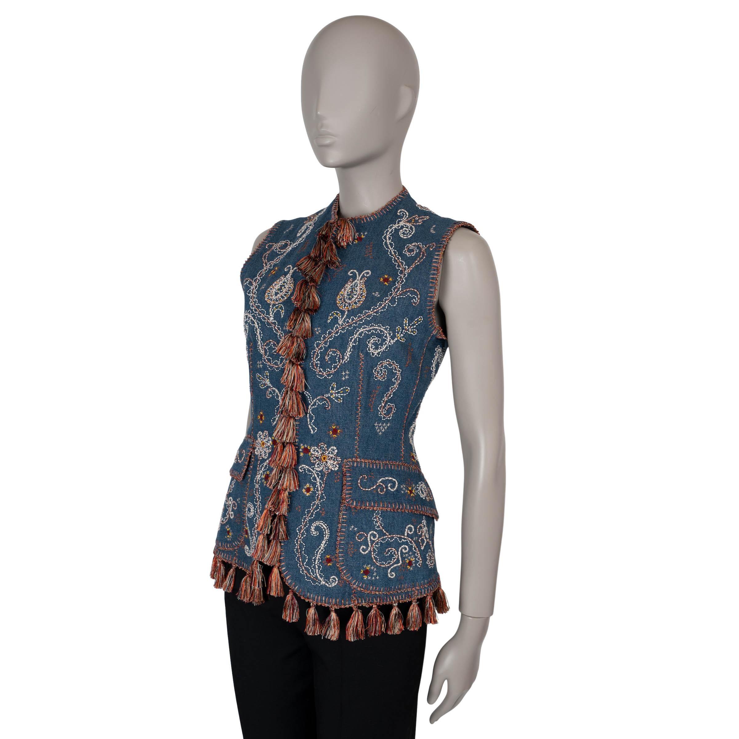 This 100% authentic Christian Dior denim vest in blue cotton showcases exquisite craftsmanship with intricate hand-embroidered paisley designs in white, yellow, and brown. Featuring a longer, fitted silhouette, it’s adorned with multicolored tassel