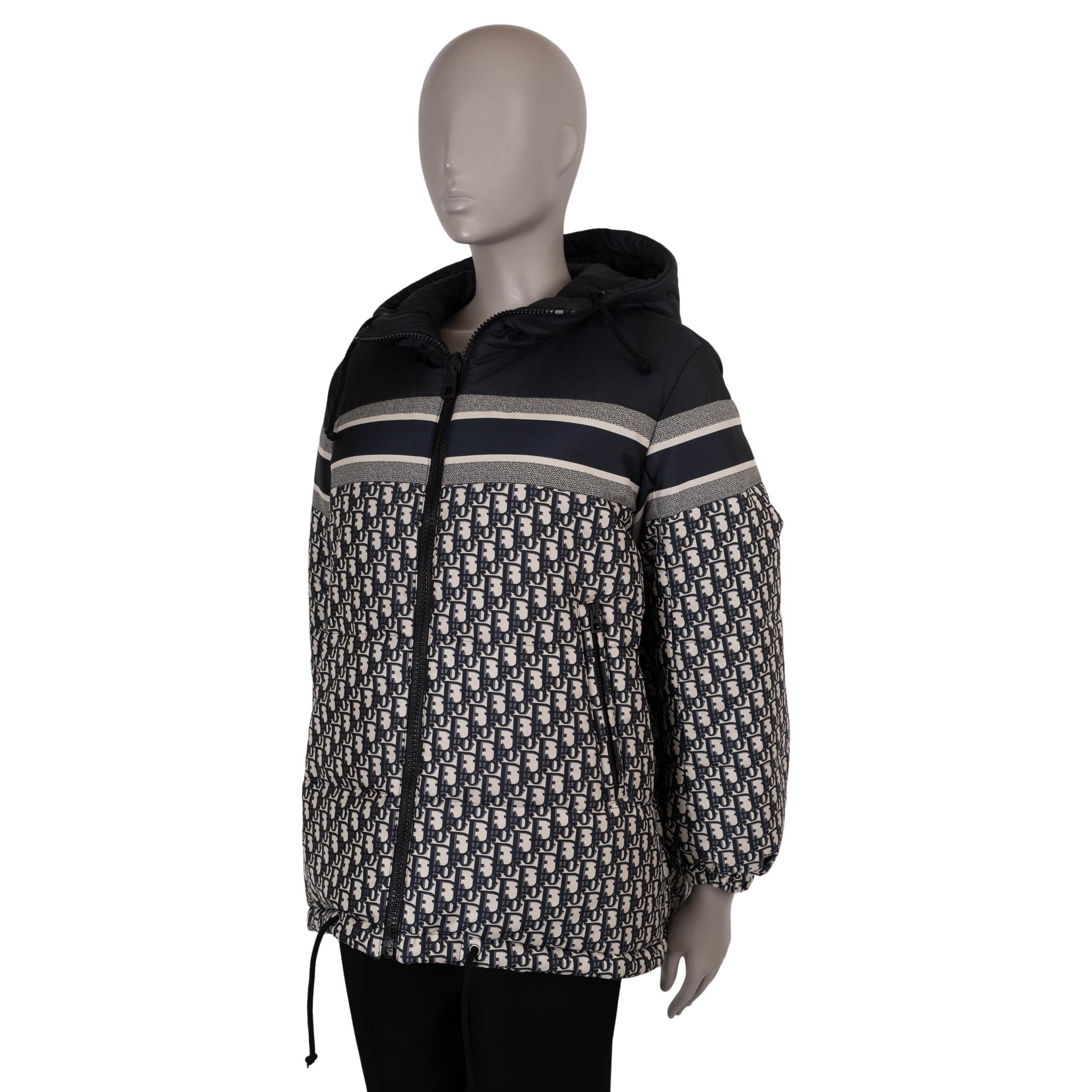 Este chaleco reversible 100% auténtico Christian Dior está confeccionado en poliéster tafetán técnico oblicuo azul y crema (100%) con el reverso en azul liso. Presenta una silueta oversize con longitud extendida, capucha con cordón, puños elásticos