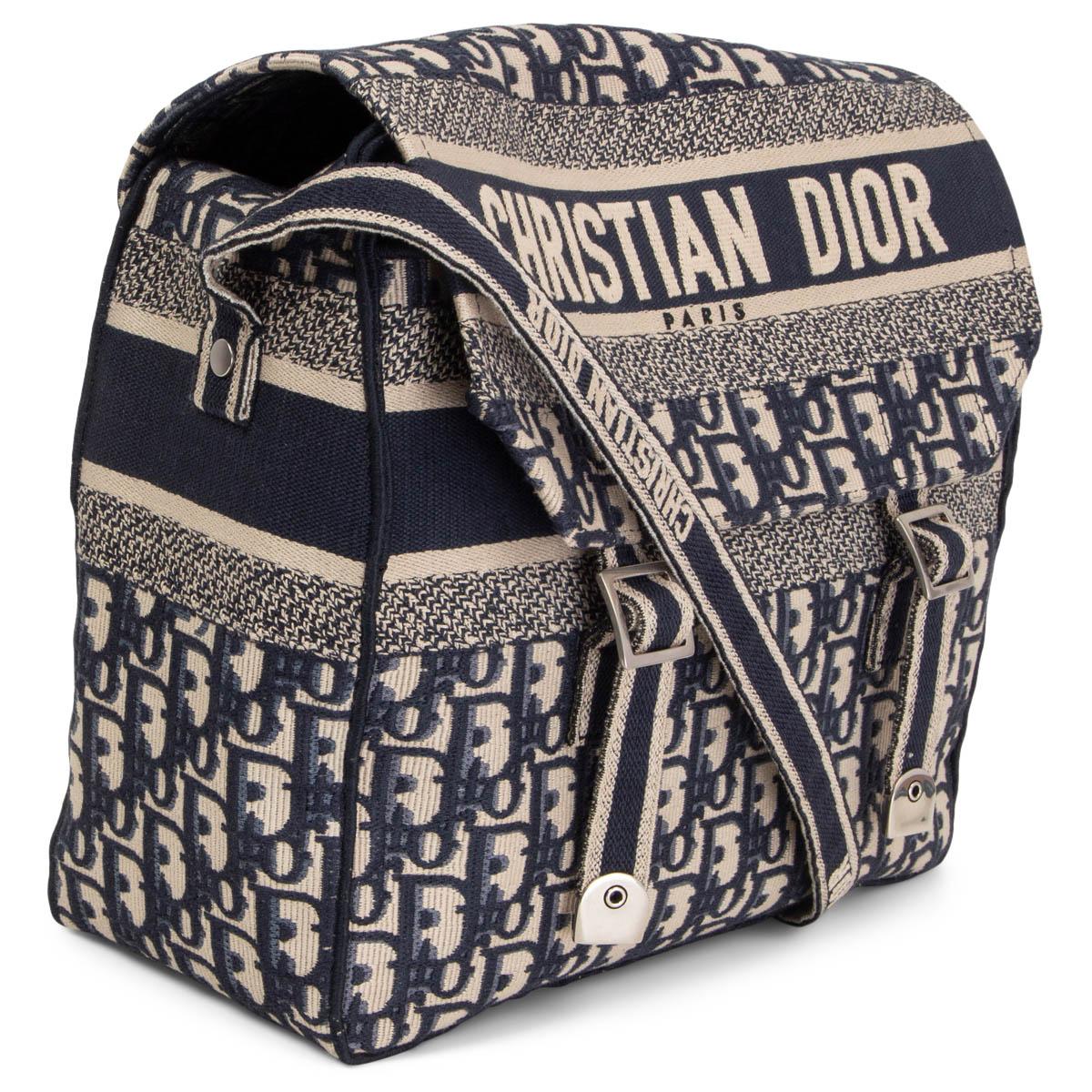 Ce sac messager Diorcamp 100% authentique de Christian Dior est réalisé en toile beige brodée du motif iconique Dior Oblique bleu. La signature audacieuse 