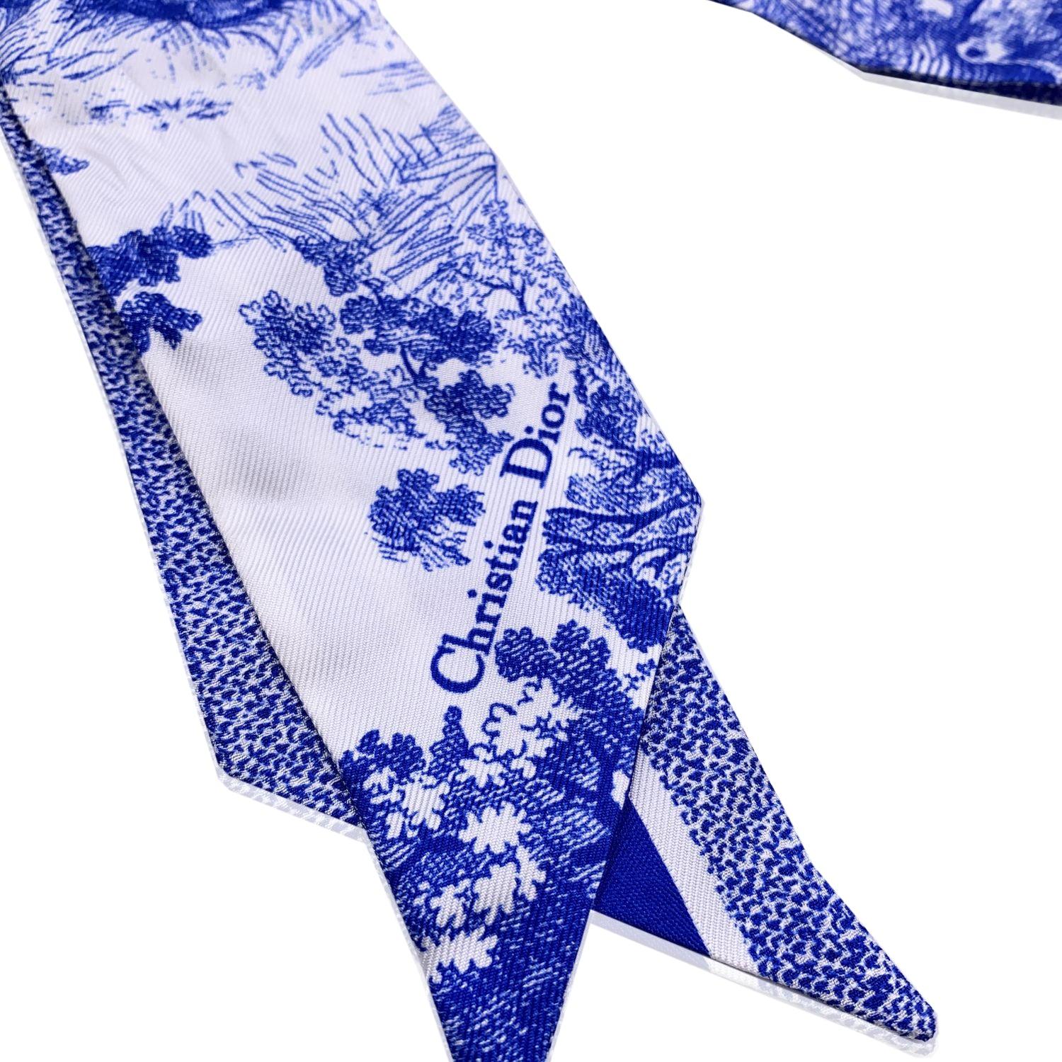 Christian Dior Blue and White Silk Twilly scarf. Toile De Jouy Sauvage print on one side and stripes with Christian Dior signature on the other. Composition: 100% Silk. Total length: 41 inches - 104.2 cm. Width: 2.25 inches - 5.7 cm. Dior tag and