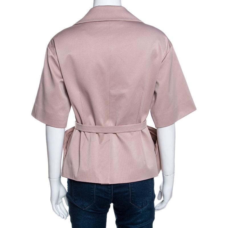 This stunning creation comes from the house of Dior. It is crafted from 100% silk and comes in a lovely shade of blush pink. It is effortlessly stylish and sophisticated. It is styled with a lapel collar, short sleeves, belt that sits at the waist