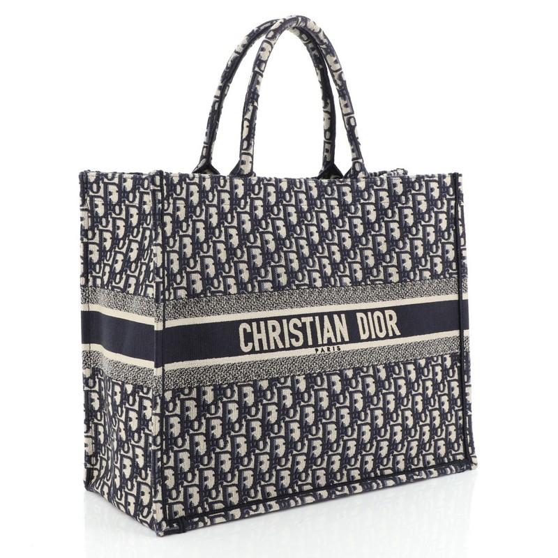 This Christian Dior Book Tote Oblique Canvas, crafted in blue oblique canvas, features dual rolled handles and Christian Dior lettering at front. It opens to a blue oblique canvas interior. 
Condition: Very good. Loss of shape on exterior, minor