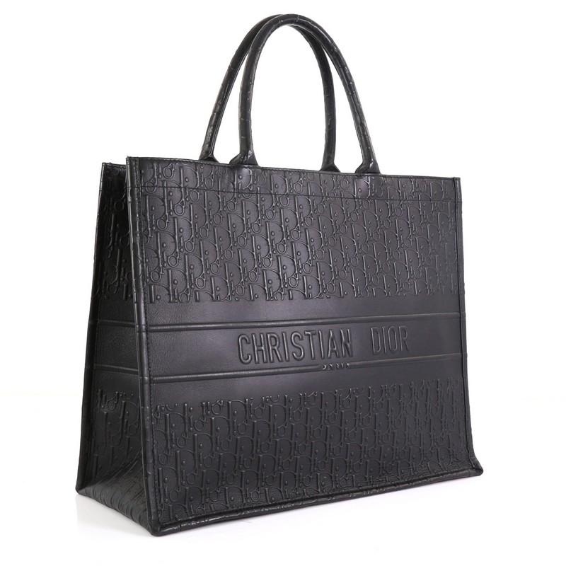 This Christian Dior Book Tote Oblique Embossed Leather, crafted in black Oblique embossed leather, features dual rolled handles and Christian Dior lettering at front. It opens to a black suede interior. 

Estimated Retail Price: $3,700
Condition: