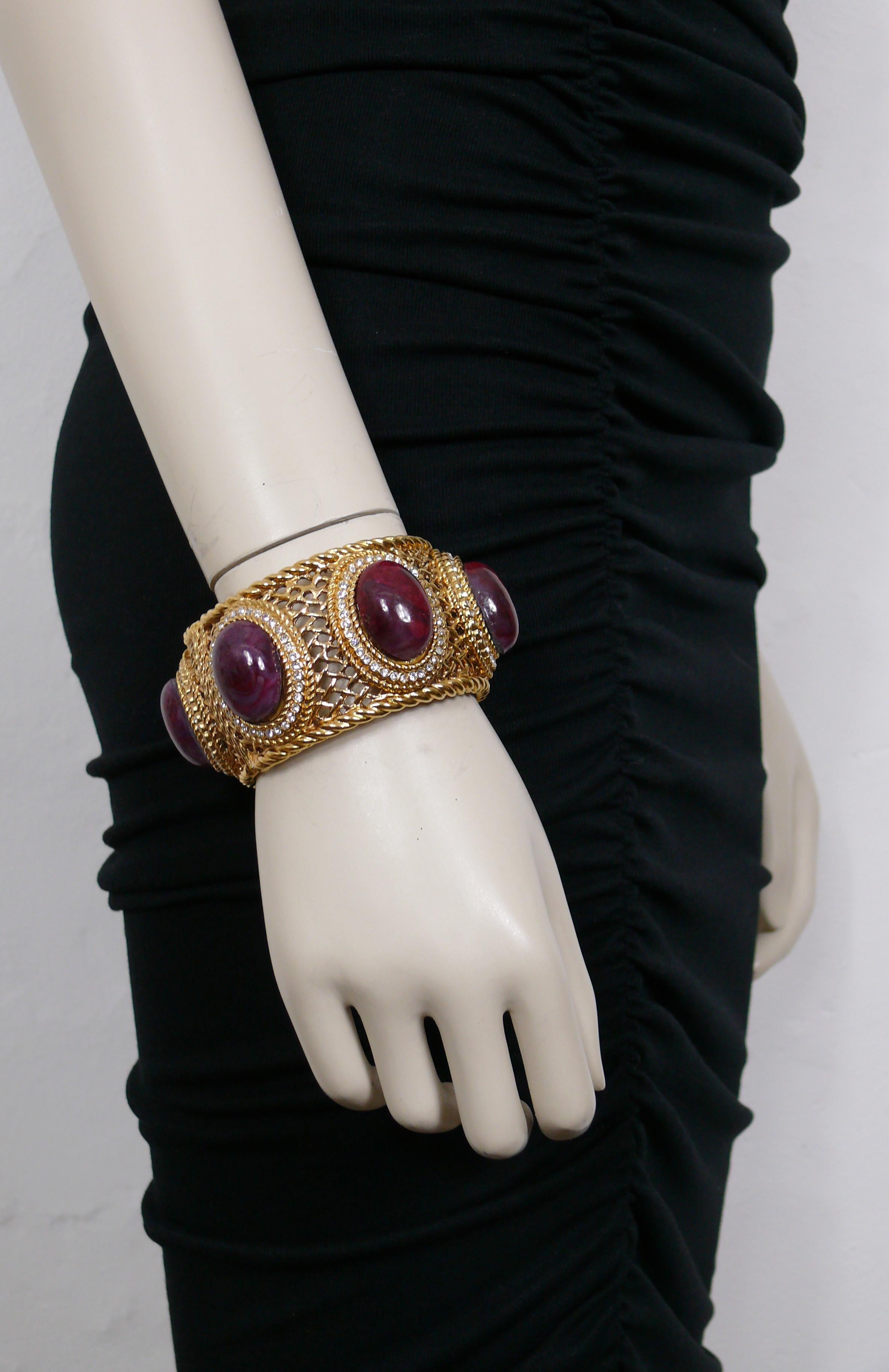 CHRISTIAN DIOR gorgeous massive gold toned rigid cuff bracelet featuring a latticework design, medallions embellished with clear crystals and red marbled oval glass cabochons simulating hard stones.

GIANFRANCO FERRE era.

This bracelet closes with