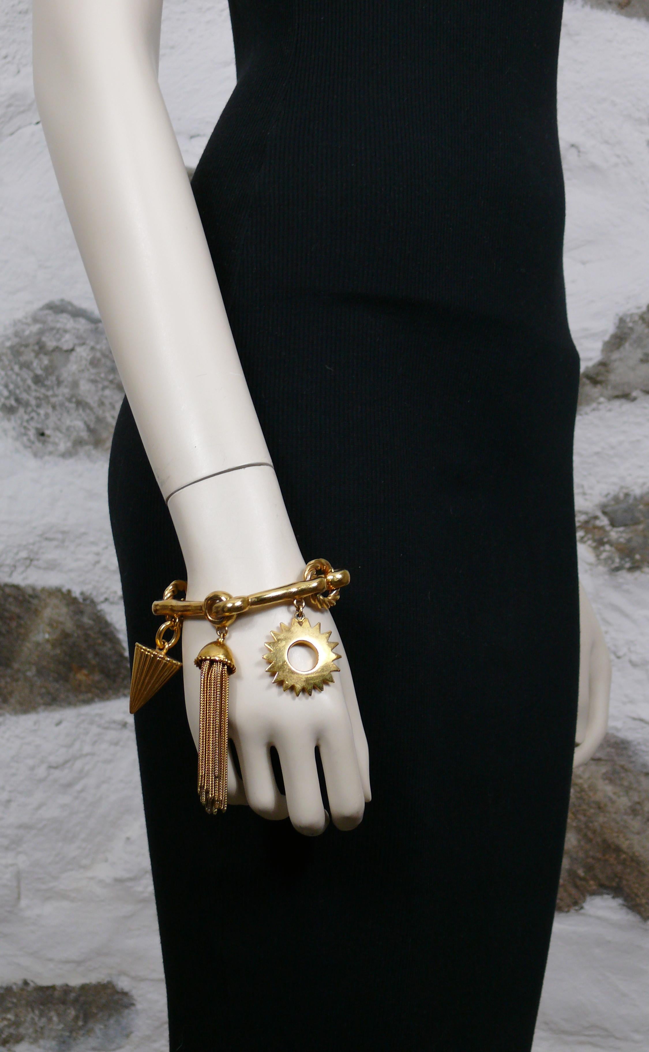 CHRISTIAN DIOR Boutique vintage rare gold toned articulated bracelet embellished with charms : ribbed conic shape, chain tassel and stylized sun.

The bracelet closes an opens thanks to an ingenious and hidden system of flattened ring.

Marked