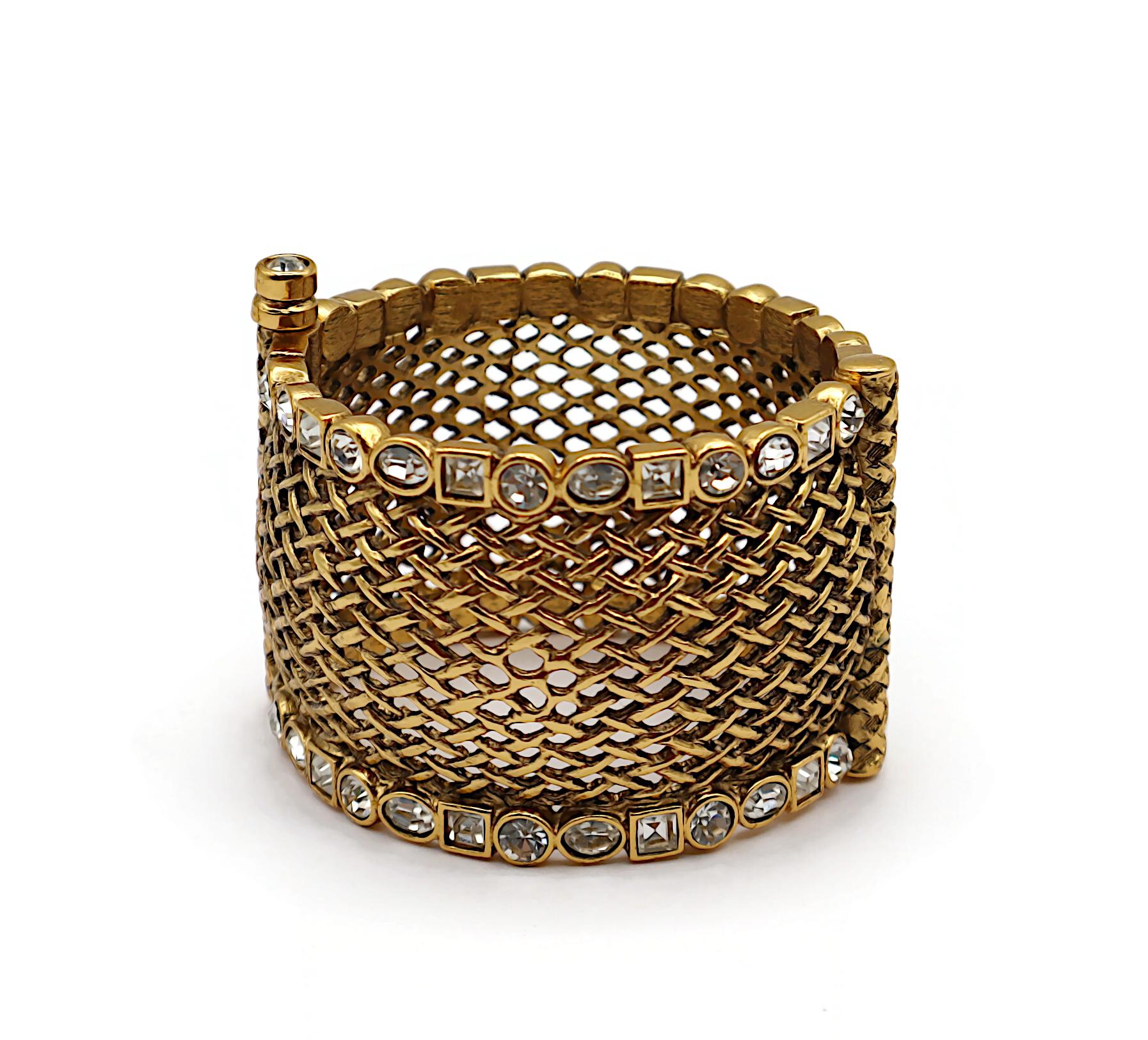 Bracciale vintage CHRISTIAN DIOR in tonalità oro con design a reticolo impreziosito da cristalli trasparenti.

Boutique CHRISTIAN DIOR in rilievo.

Misure indicative: circonferenza interna circa 18,54 cm (7,30 pollici) / larghezza circa 4,5 cm (1,77
