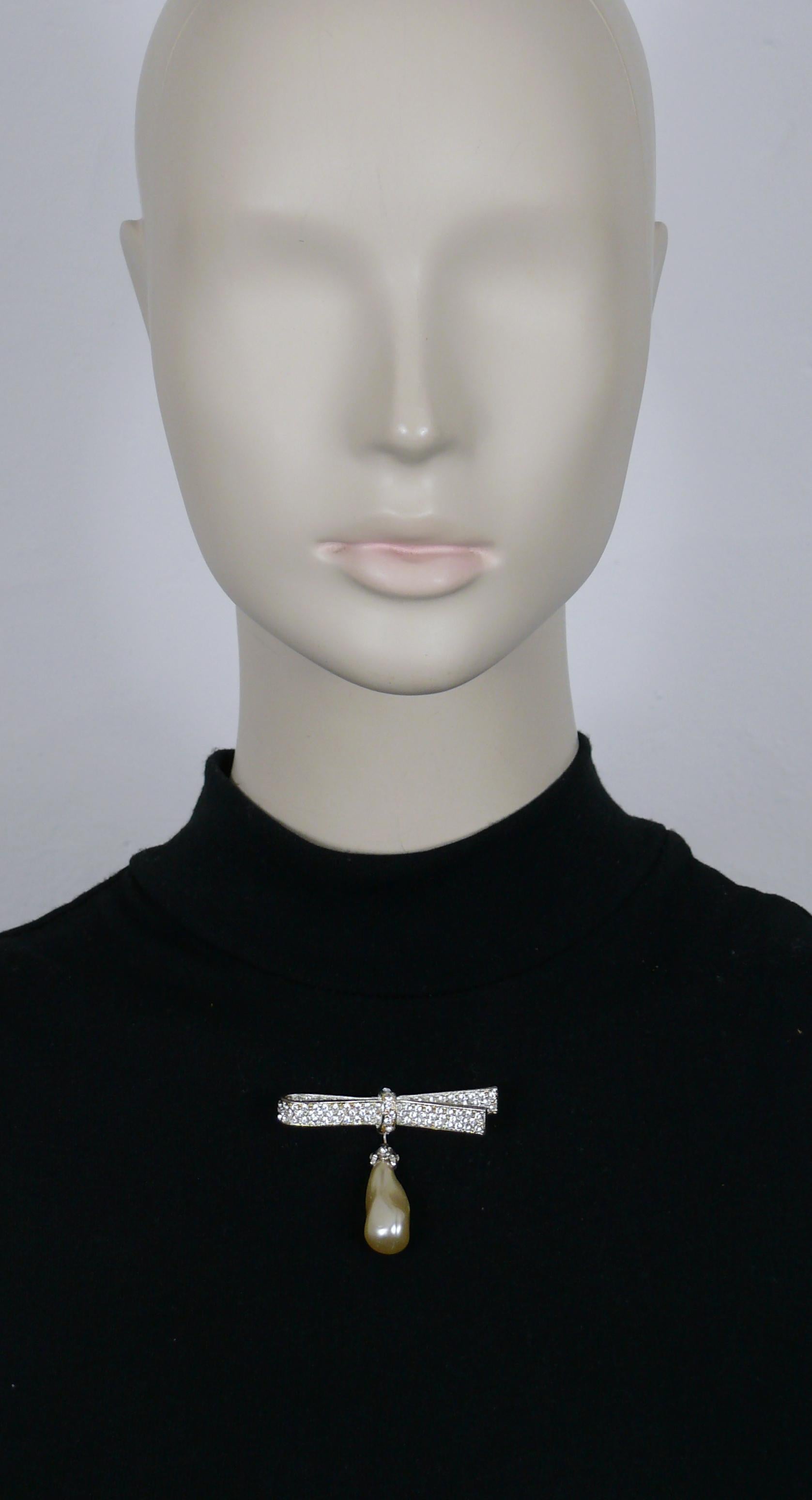 CHRISTIAN DIOR Boutique vintage silver tone ribbon bow brooch embellished with clear crystals and a dangling faux pearl drop.

Marked CHRISTIAN DIOR Boutique.

Indicative measurements : max. width approx 5.7 cm (2.24 inches) / max. height approx.