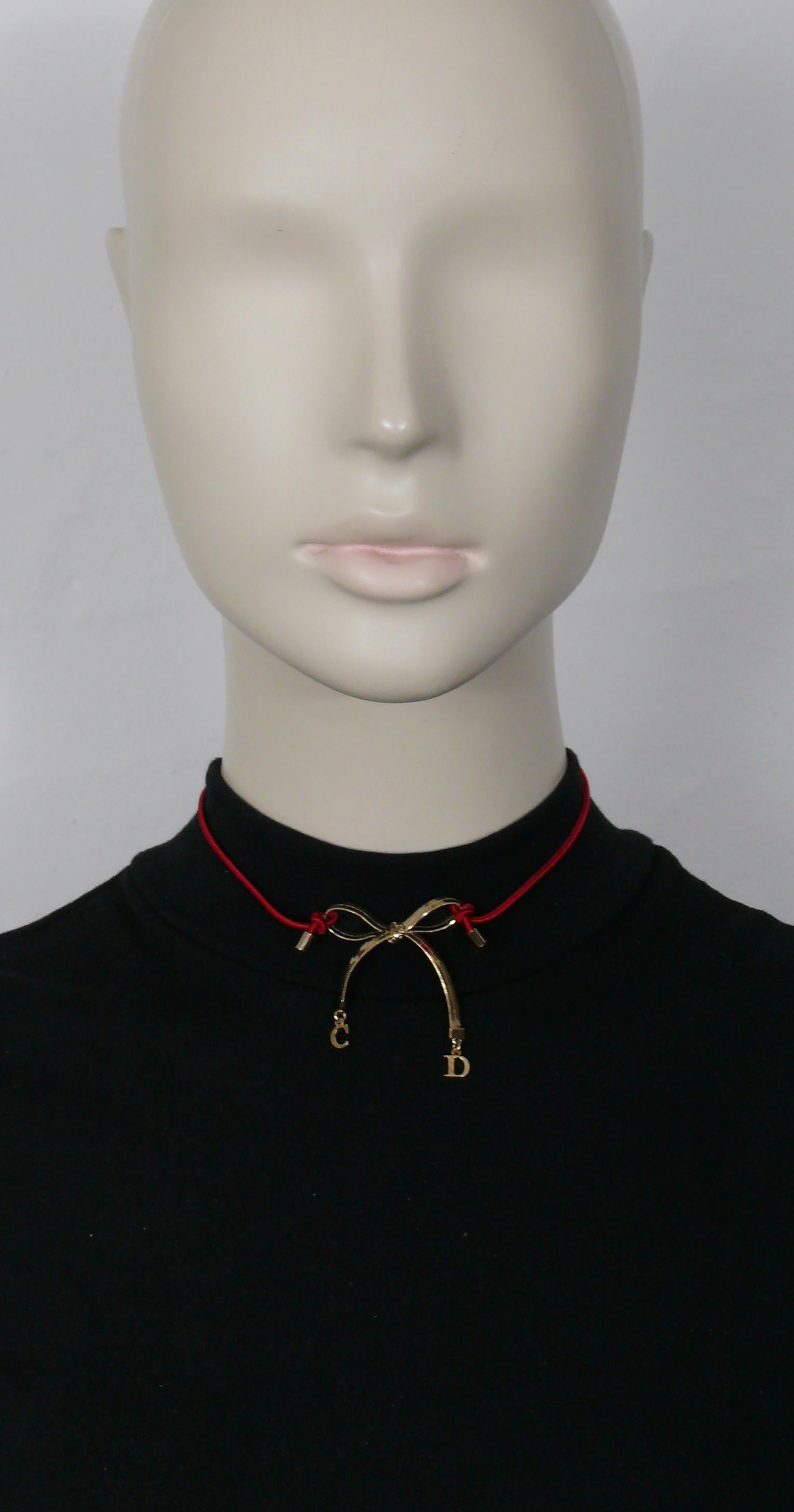 CHRISTIAN DIOR choker necklace featuring a gold tone bow and C D initial charms, red elasticated strap.

Lobster clasp closure.
Adjustable length.

Embossed DIOR.

Indicative measurements : adjustable length from approx. 33 cm (12.99 inches) to