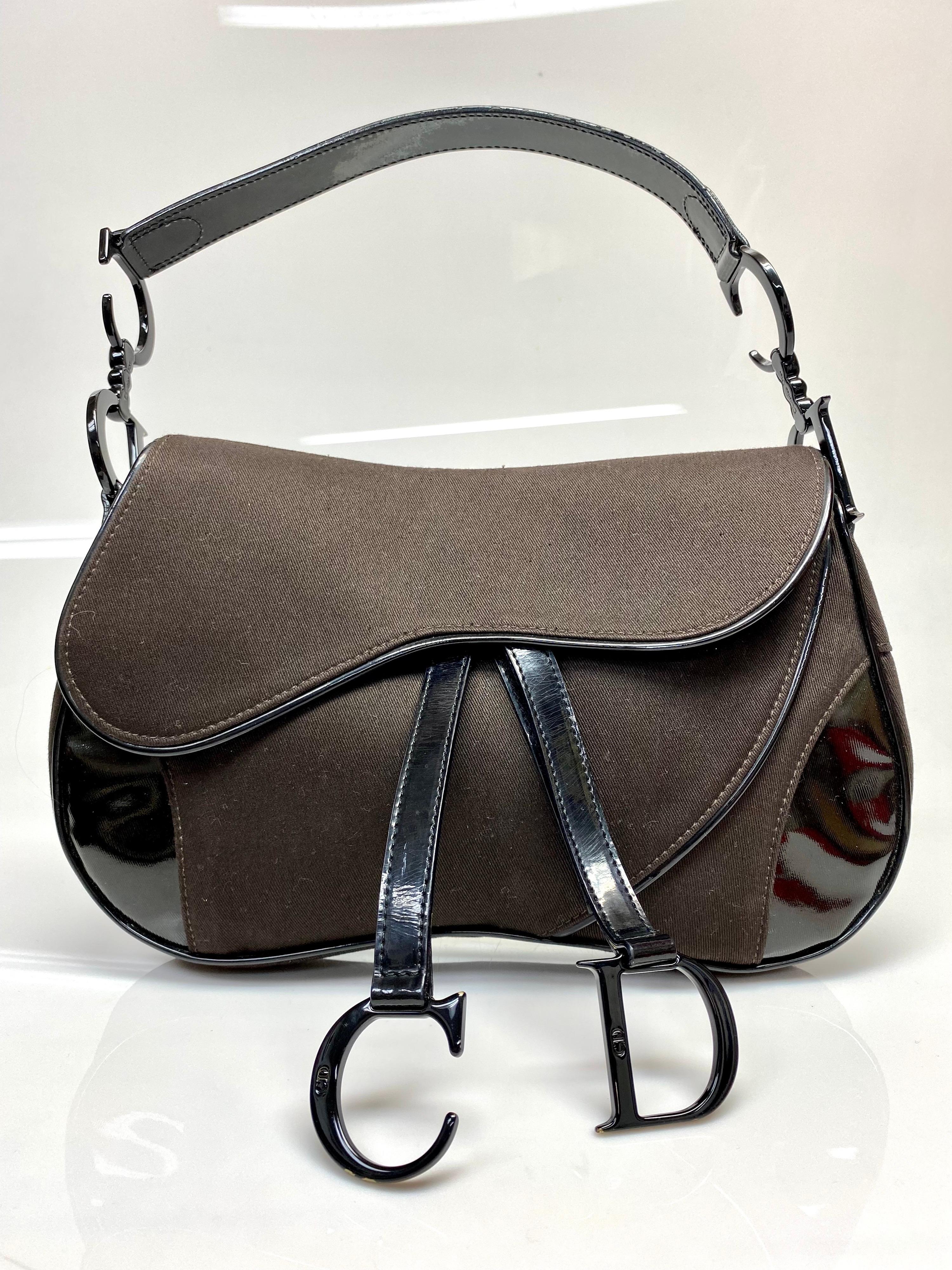 The iconic saddle bag is one of Christian Dior's most famous designs. This rare beauty features patent black hardware with the CD logo adorning both sides of the bag. The chocolate brown color will go perfect with any fashionista's wardrobe. The bag
