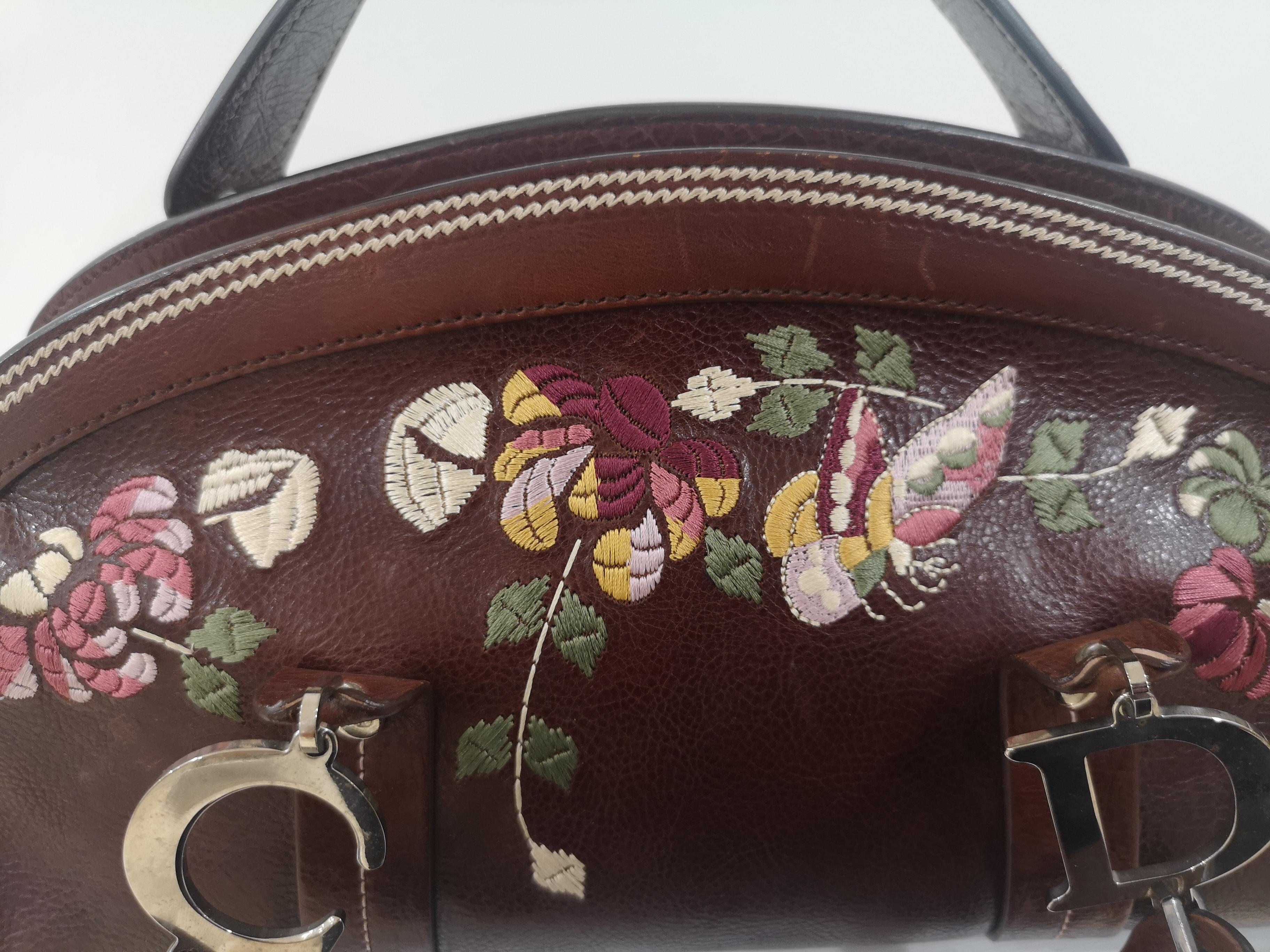 Burnt red leather Christian Dior handle bag with silver-tone hardware, multicolor floral embroidery at front, logo at handles, dual flat top handles featuring logo accents, chocolate brown Diorissimo canvas lining, single pocket with zip closure and