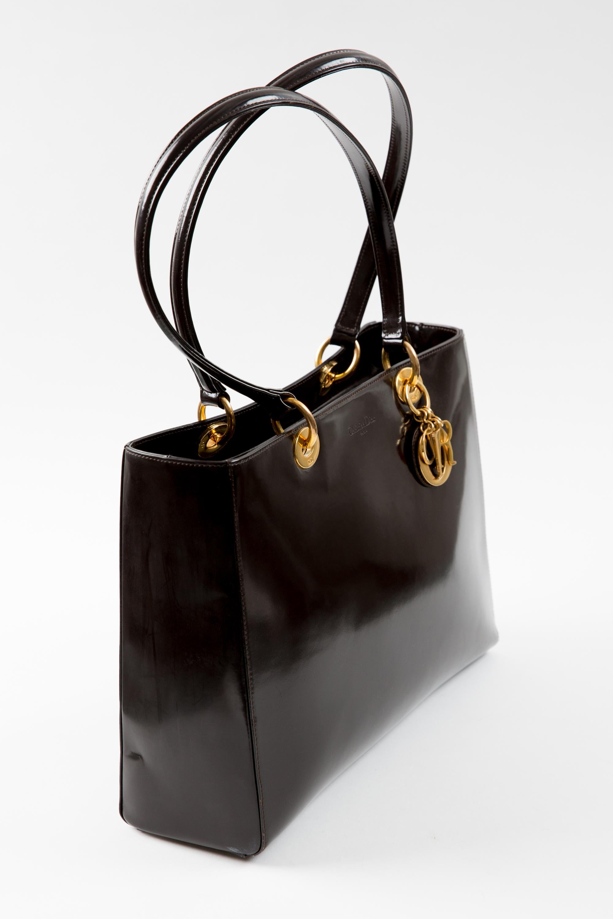 Christian Dior brown shiny leather large “Lady Dior” shoulder tote bag featuring gold-tone front charms “CD”, gold-tone hardware, large two top leather handles, a straight fitting, a top zip opening, inside brown logo lining, an inside logo plaque.