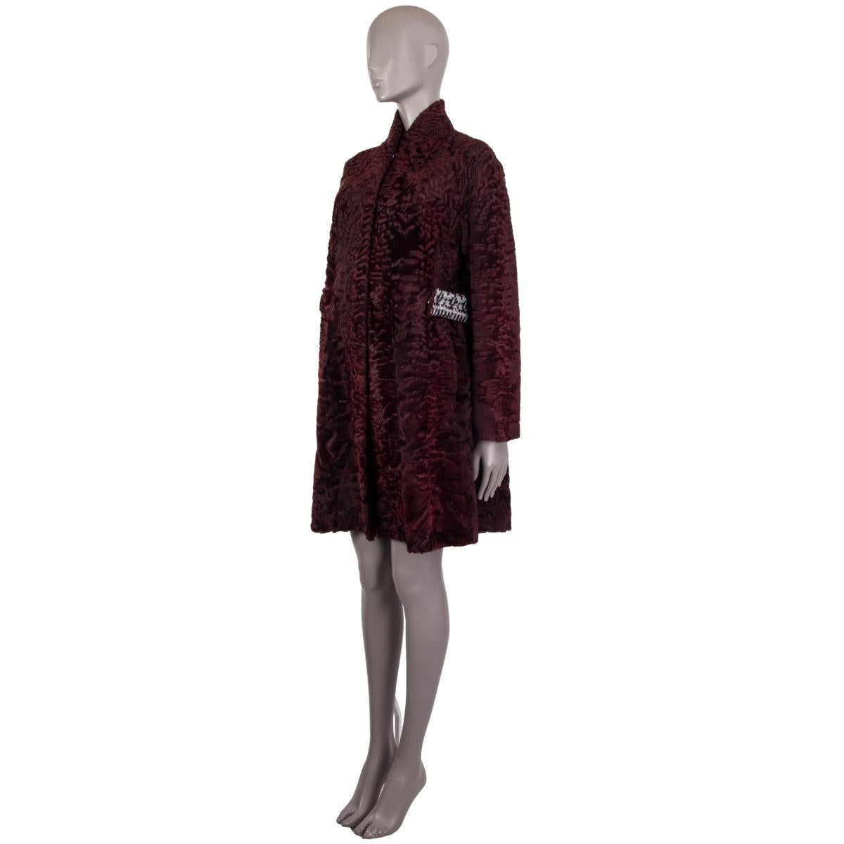 Christian Dior coat in burgundy Astrakhan lamb fur coat. With split neck and two slit pockets on the sides. Featured reversible waistband in fur on one side and burgundy and white sequins on the reverse with two snap closures. Closes with concealed