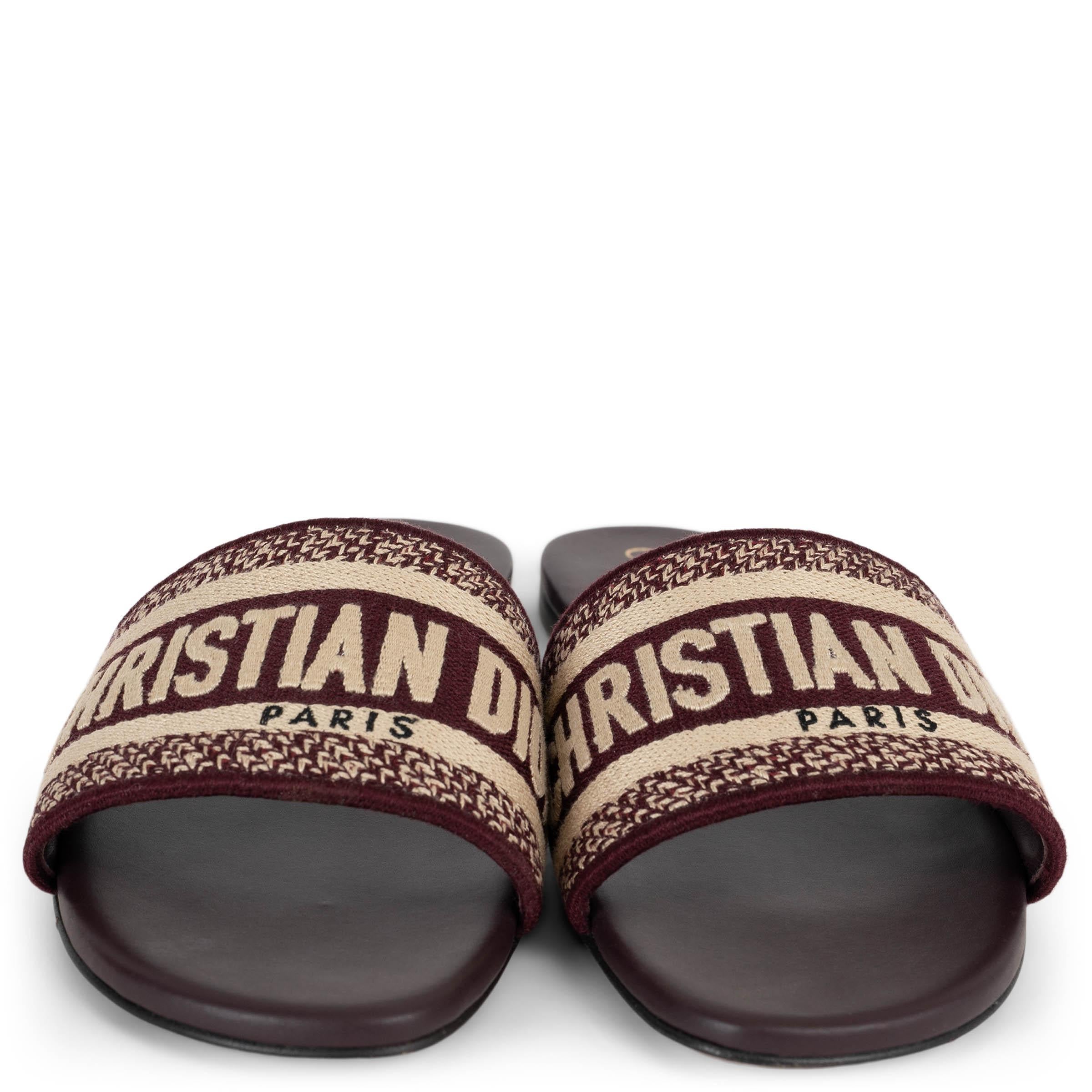Christian Dior Dway slide sandals in burgundy embroidered cotton. Feature the iconic CHRISTIAN DIOR PARIS signature across the wide band. Flat silhouette set on leather soles for an elegant yet effortless finish. Have been worn and are in excellent