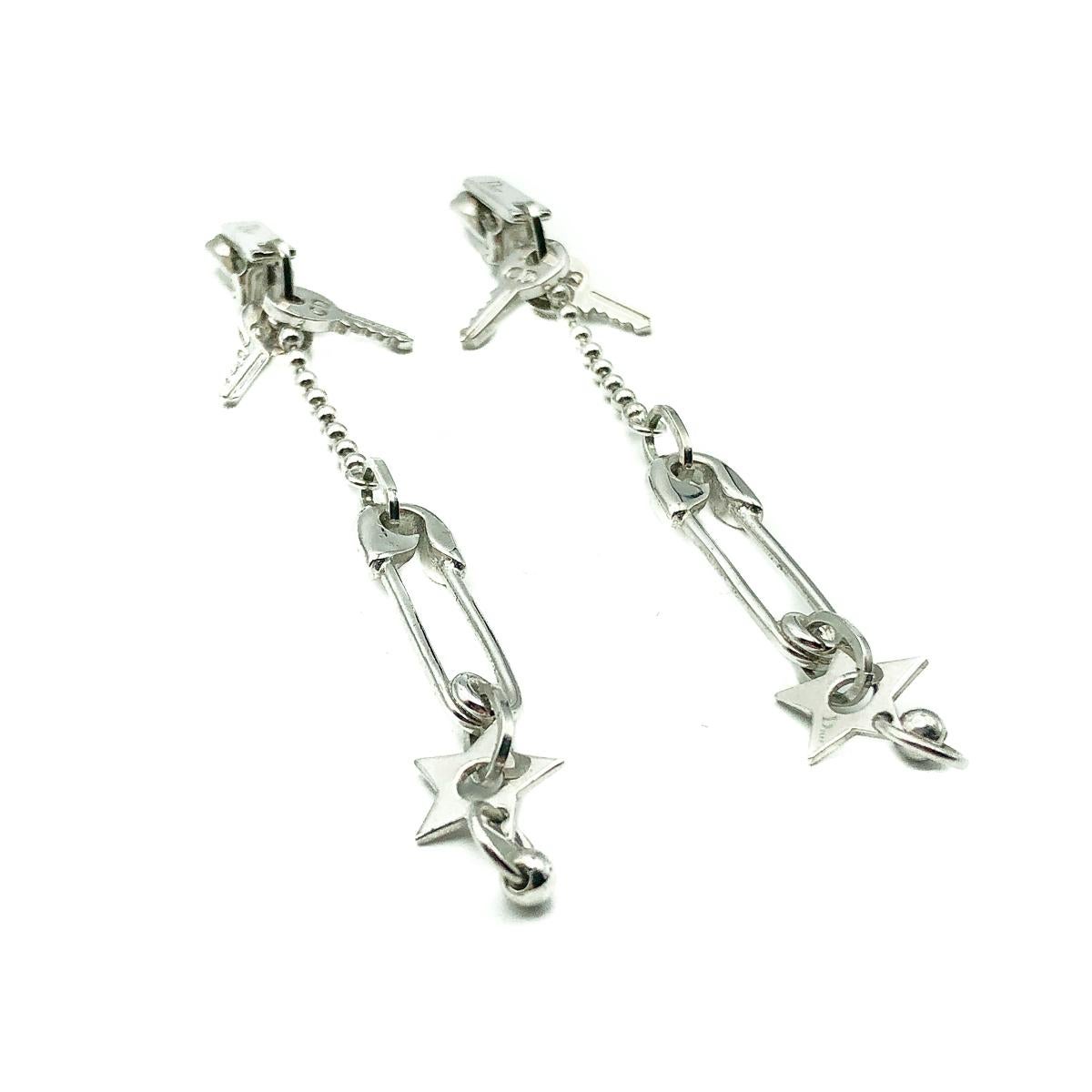 Fun and funky, Christian Dior Safety Pin Earrings from the Galliano era. Crafted in rhodium plated metal. Featuring emblems of the house and collections of the time; safety pins, logo keys and stars. In very good vintage condition, signed, approx.