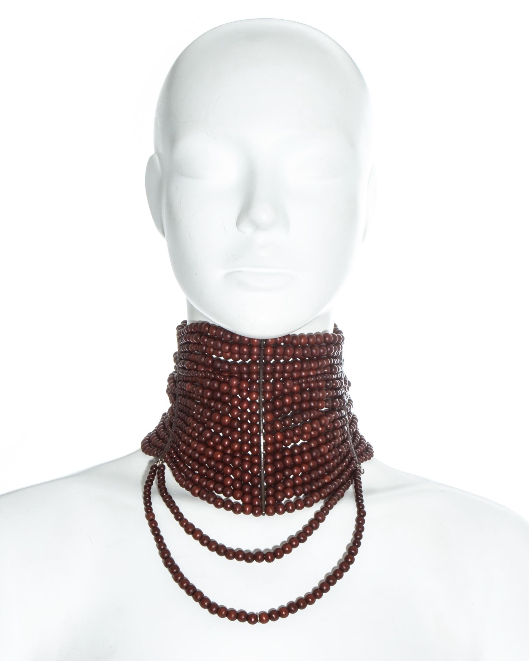 Christian Dior by John Galliano; Eighteen strand 'Maasai' choker necklace. Mahogany brown wooden beads, 3 curved metal horn shaped bands which sculpt the neck, chain fastening at the rear, and two hanging strands at the centre front.   

Fall-Winter