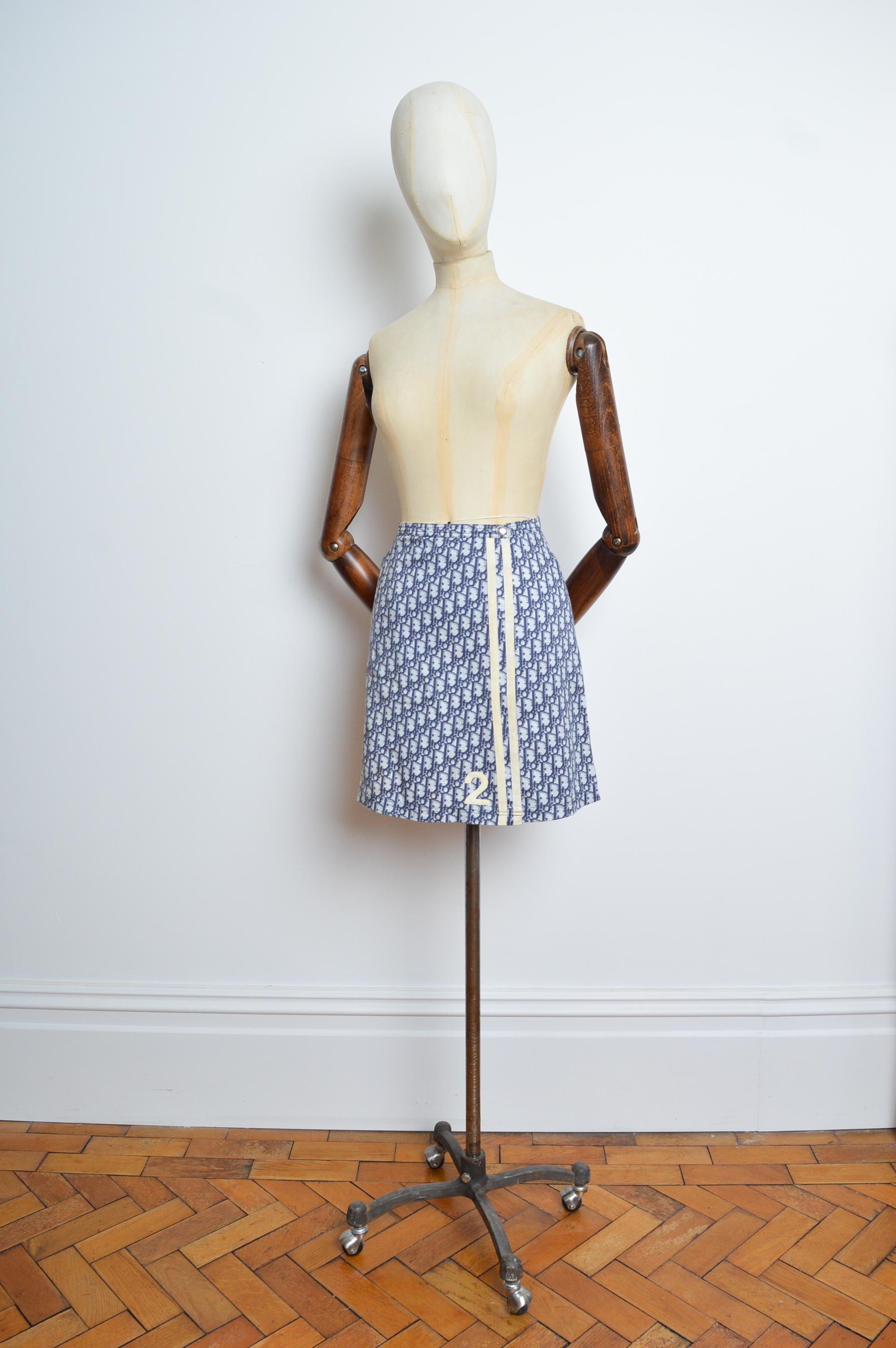 2005 Christian Dior monogram, wrap around mini skirt crafted from Blue trotter 'DIOR' monogram print cloth for the Junior label, with racing stripe detail and number 2 appliqué. 
Size; 26 to 27 inch waist - UK 6-8.
Measurements are provided in