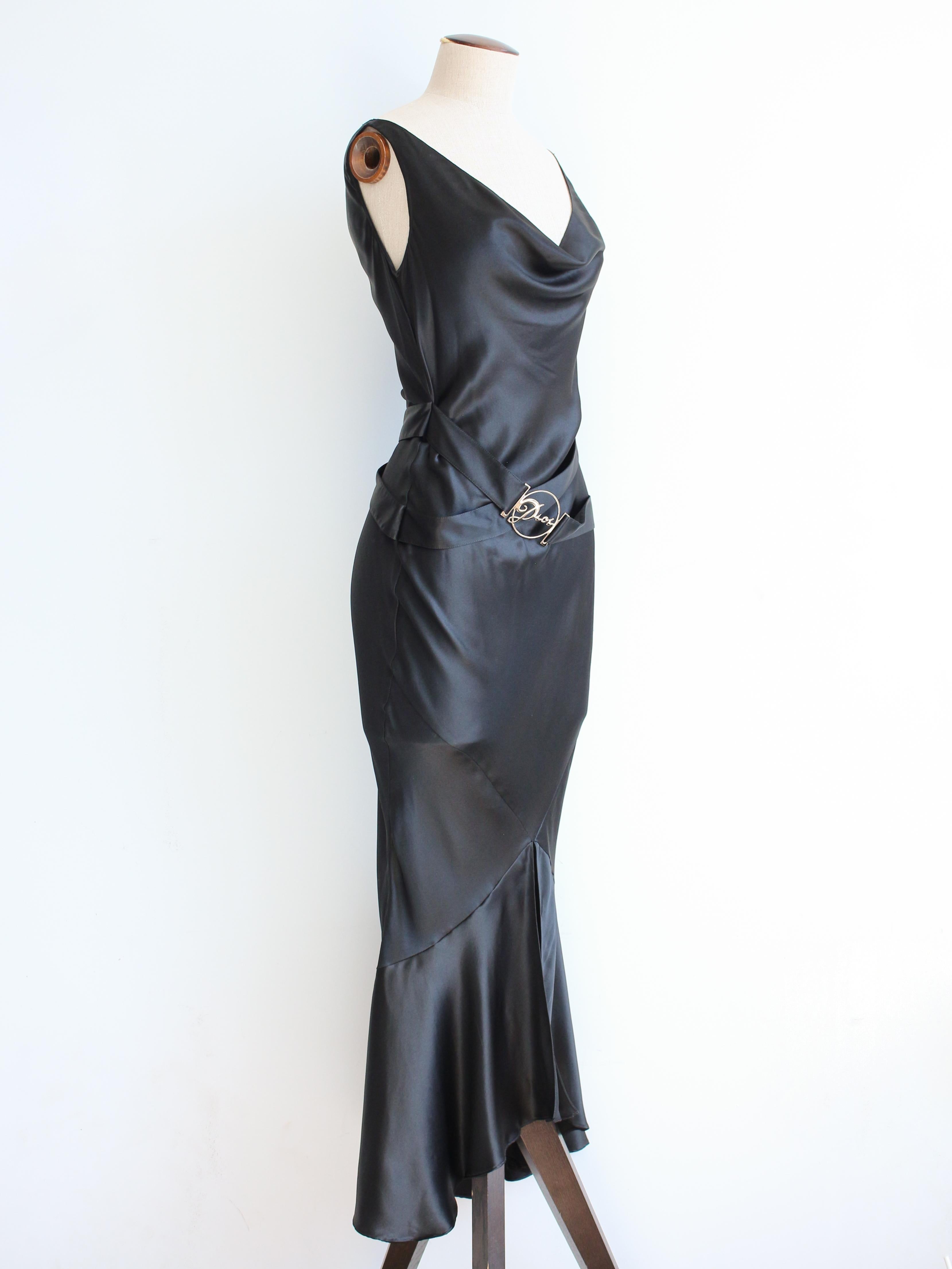 Christian Dior by John Galliano Automne/Hiver 2004 - Robe noire en satin de soie coupée en biais avec col bénitier, jupe entraînée fendue sur le devant et ceinture à logo métallique.

Taille étiquetée FR36.

En très bon état général, il y a quelques