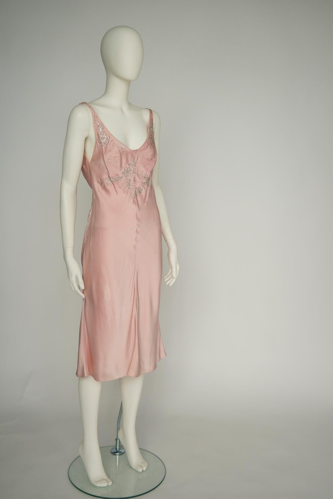From the 2004 Fall-Winter collection, this John Galliano for Christian Dior cocktail dress is cut from refined light pink silk-satin that delicately skims the figure. Reminiscent of styles worn in the 30’s and 40’s, the dress is beautifully
