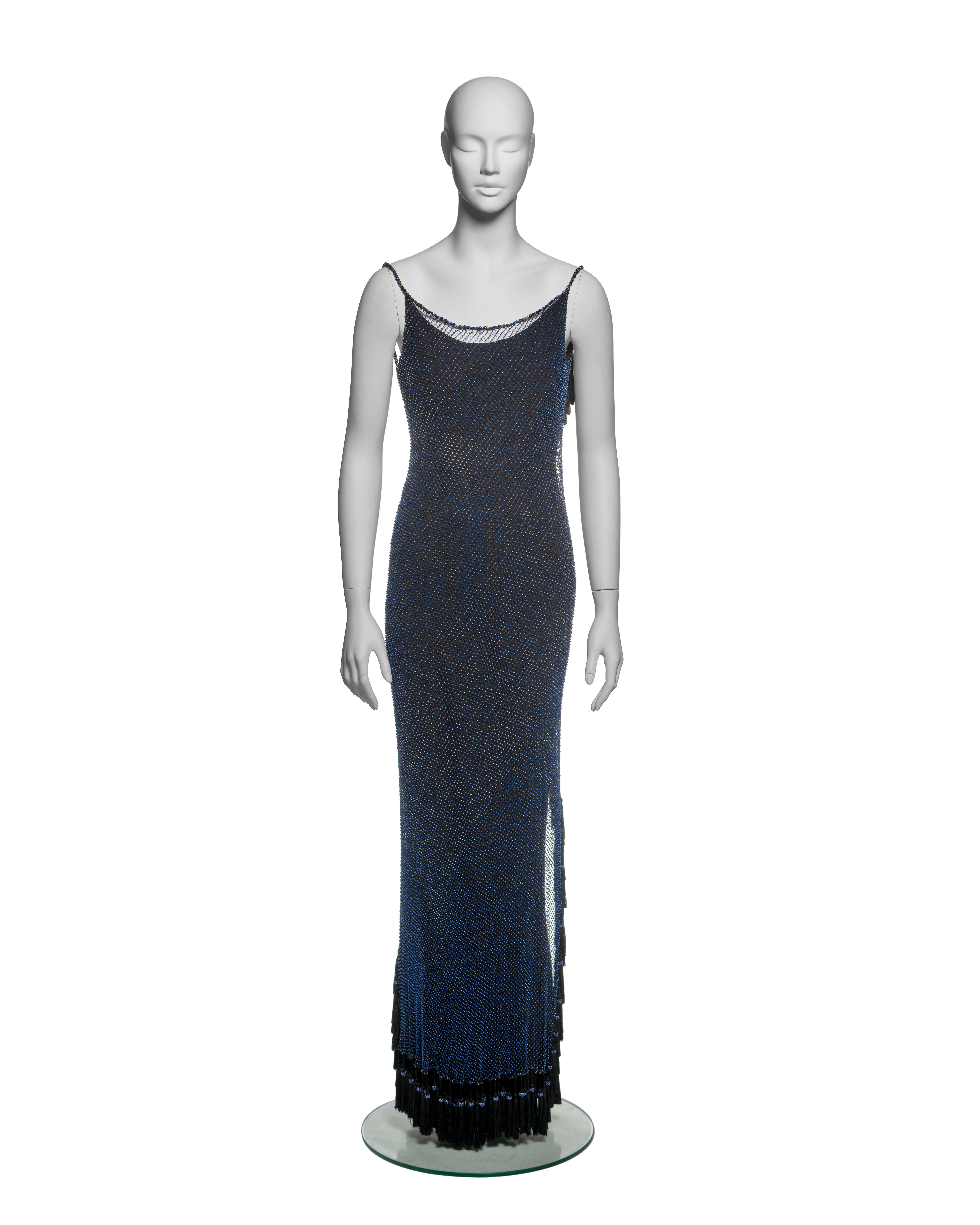 This Christian Dior by John Galliano dress from the Spring-Summer 1998 collection is crafted from intricately beaded net fabric secured over a bias-cut slip dress. The net features a diagonal grid of seed beads in shades of blue, with the neckline