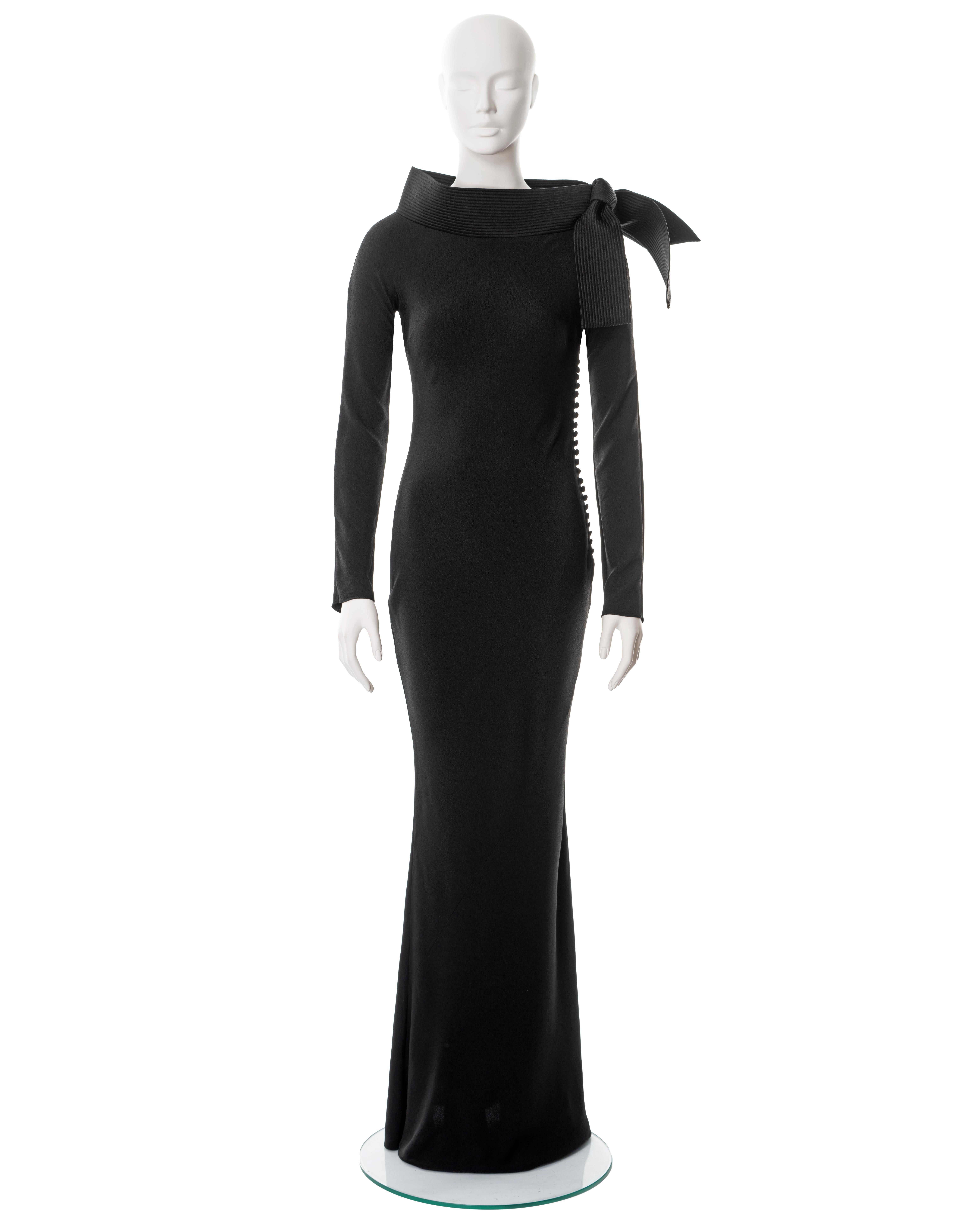 ▪ Christian Dior black evening dress 
▪ Designed by John Galliano
▪ Sold by One of a Kind Archive
▪ Fall-Winter 1999
▪ Constructed from black bias-cut satin-backed crêpe 
▪ Boat neck with standing collar and large bow to one shoulder 
▪ Long fitted